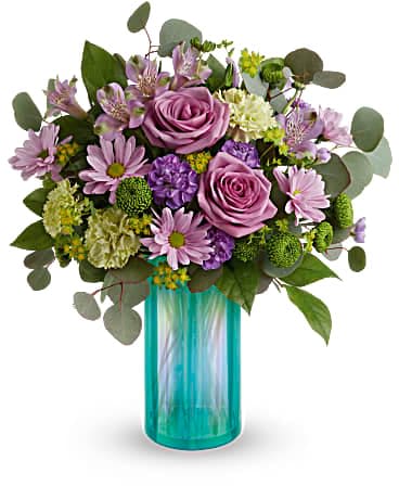 Teleflora's Iridescent Dream Bouquet - Like a fresh spring breeze, this soft lavender bouquet in an iridescent aqua glass vase invigorates the senses. Lavender roses, lavender alstroemeria, green carnations, miniature purple carnations, lavender daisy spray roses and green button spray chrysanthemums are accented with bupleurum and silver dollar eucalyptus. Delivered in an Iridescent Dream Vase.
