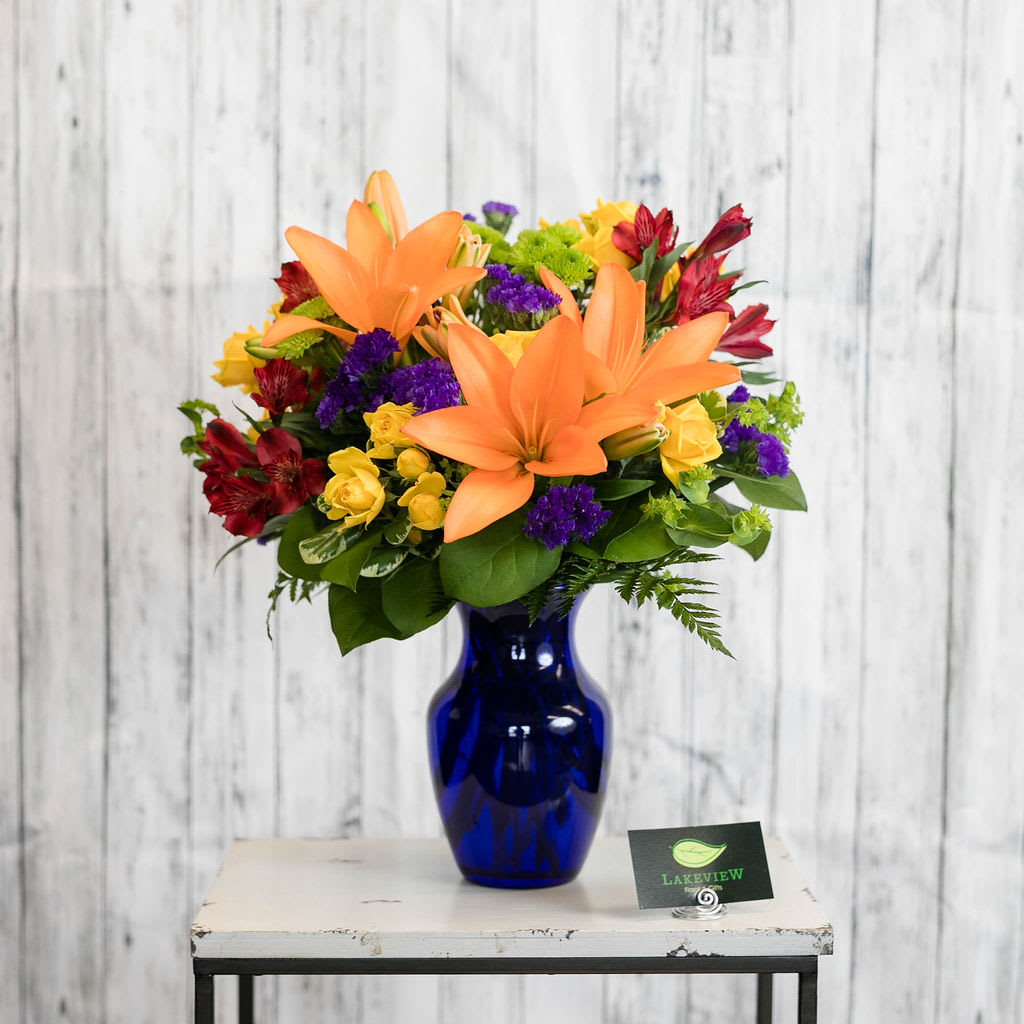 Celebration - Perfect to celebrate any occasion is this bright blue vase filled with brightly colored lilies, altroemeria and statice.  Approximate Dimensions: 20&quot; H x 14&quot; W