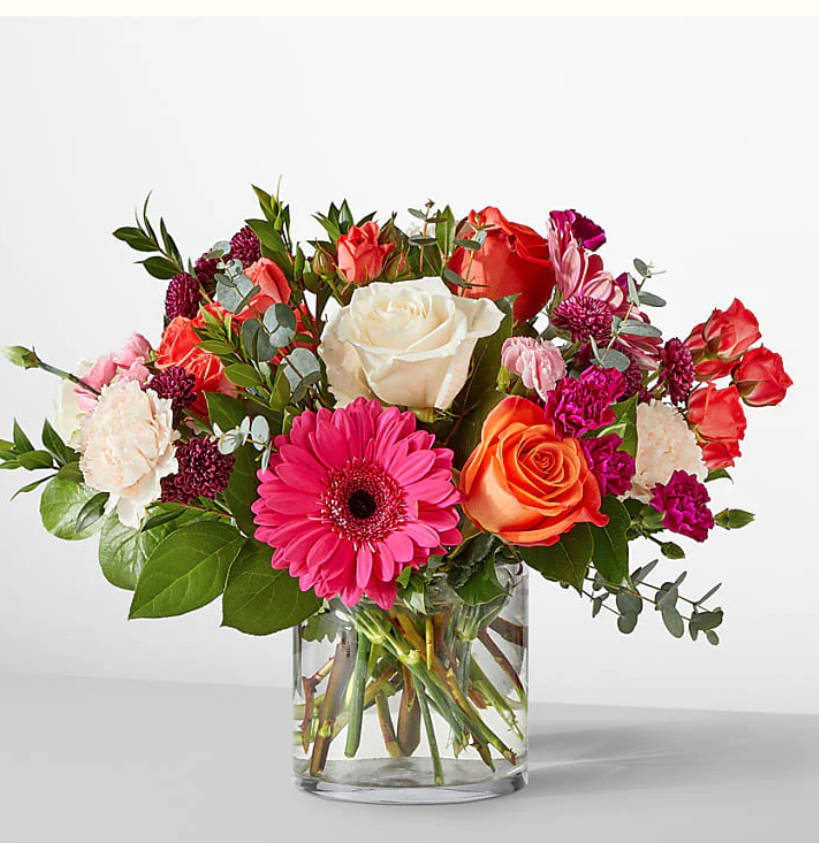 Sara Smile - Gerber Daisies, orange / pink roses / mini carnations with greenery in a glass vase!