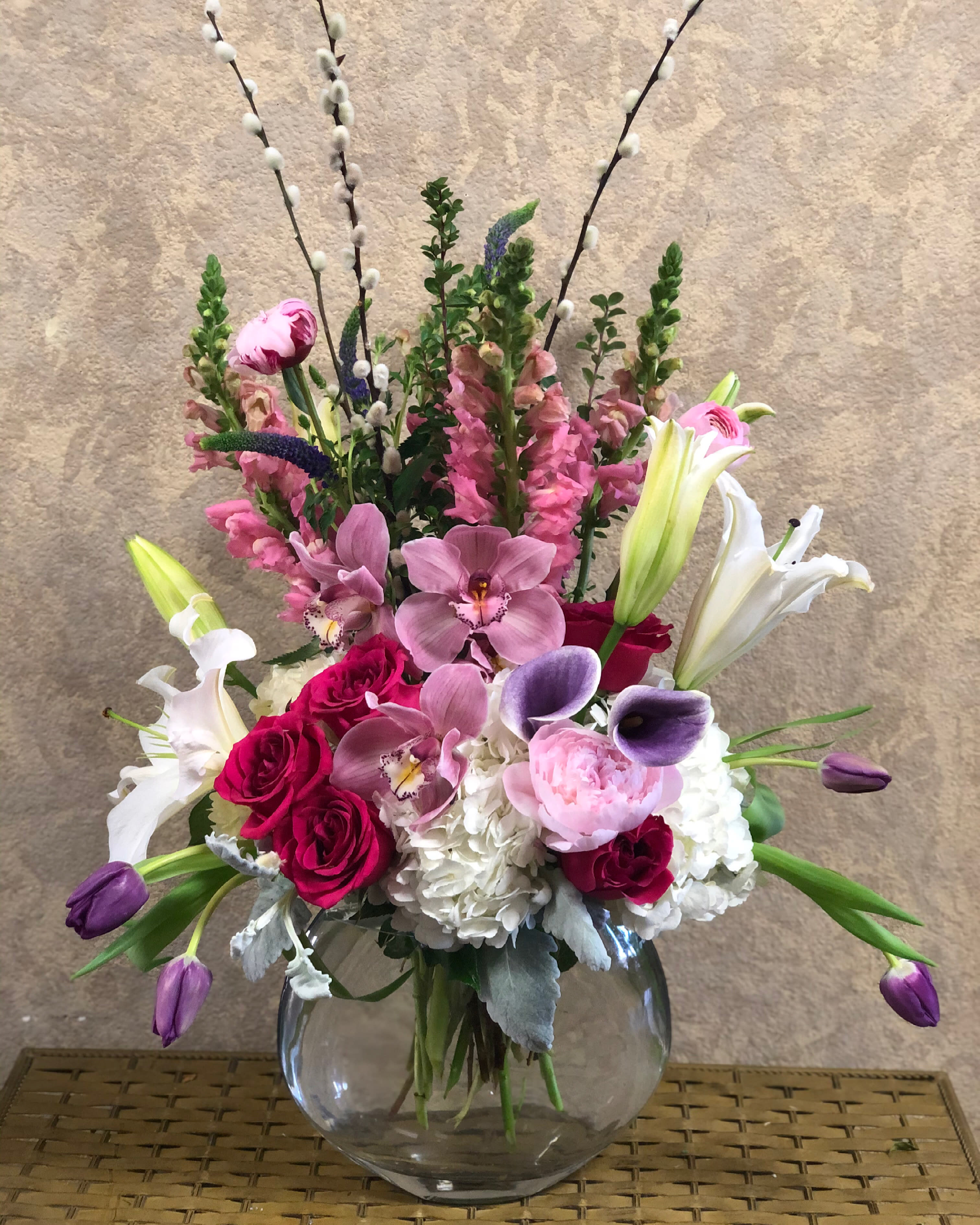 Toi e Moi - You, Tù, Toi.  Type of Flowers: Purple Calla Lilies, Pink Peonies, Pink Cymbidium Orchids, Hot Pink Roses, White Hydrangeas, White Stargazers, Pink SNapdragon, Pussy Willow, Dusty Miller and more in a round, skinny, clear vase. Availability: All year round Design View: Symmetric Front Facing View Photo shown: Standard 