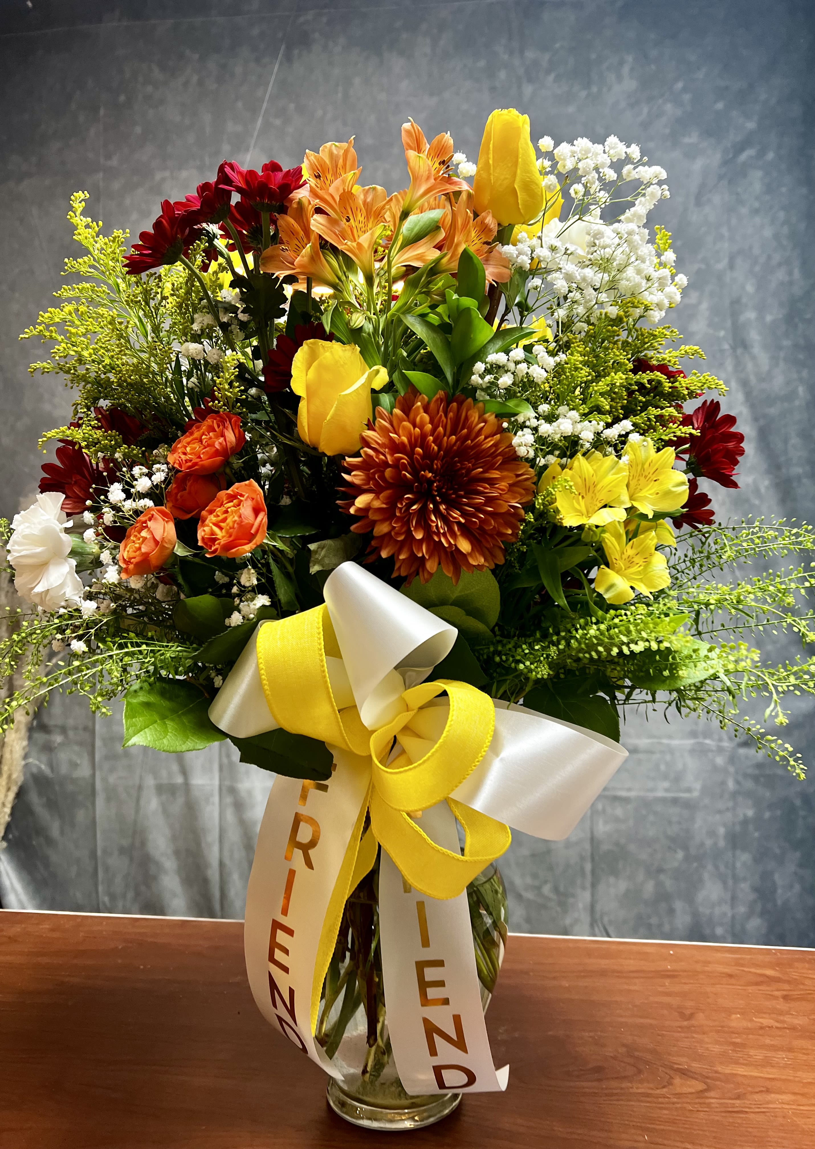 Fall Beauty  -  Introducing our Fall Beauty Vase! This stunning arrangement features vibrant mums, alstroemeria, roses, and spray roses, perfectly capturing the essence of the season. It’s an ideal centerpiece for your home or a lovely gift for someone special. Order yours today and bring the beauty of fall indoors! The ribbons can be customized with a special name or leaving them blank  