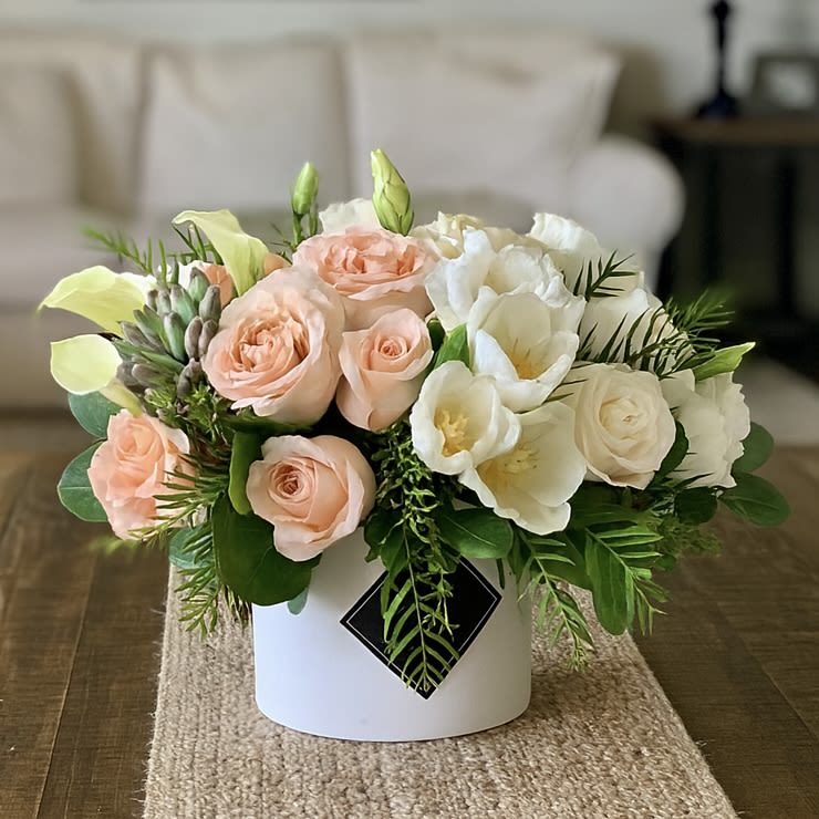 Sunset Passion - Introducing Sunset Passion, a truly stunning flower arrangement that will bring incredible bursts of beauty into your home. Our vibrant combination of breathtaking peach and white roses, exquisite white tulips, striking white calla lilies, and delightful succulents are guaranteed to take your breath away.  No matter what the occasion is – be it a romantic evening in or an anniversary present – this irresistible display of earth’s natural wonders will demonstrate your undying commitment to the ones you love. Expertly arranged in our whisper-white matte cylinder vase, these florals are bound to create an exquisite aesthetic that will wow everyone you meet.  With its bright tones of peach and white, our Sunset Passion brings a magical sense of enchantment to any living space. Make sure to get yours today – after all, passionate love deserves passionate flowers!
