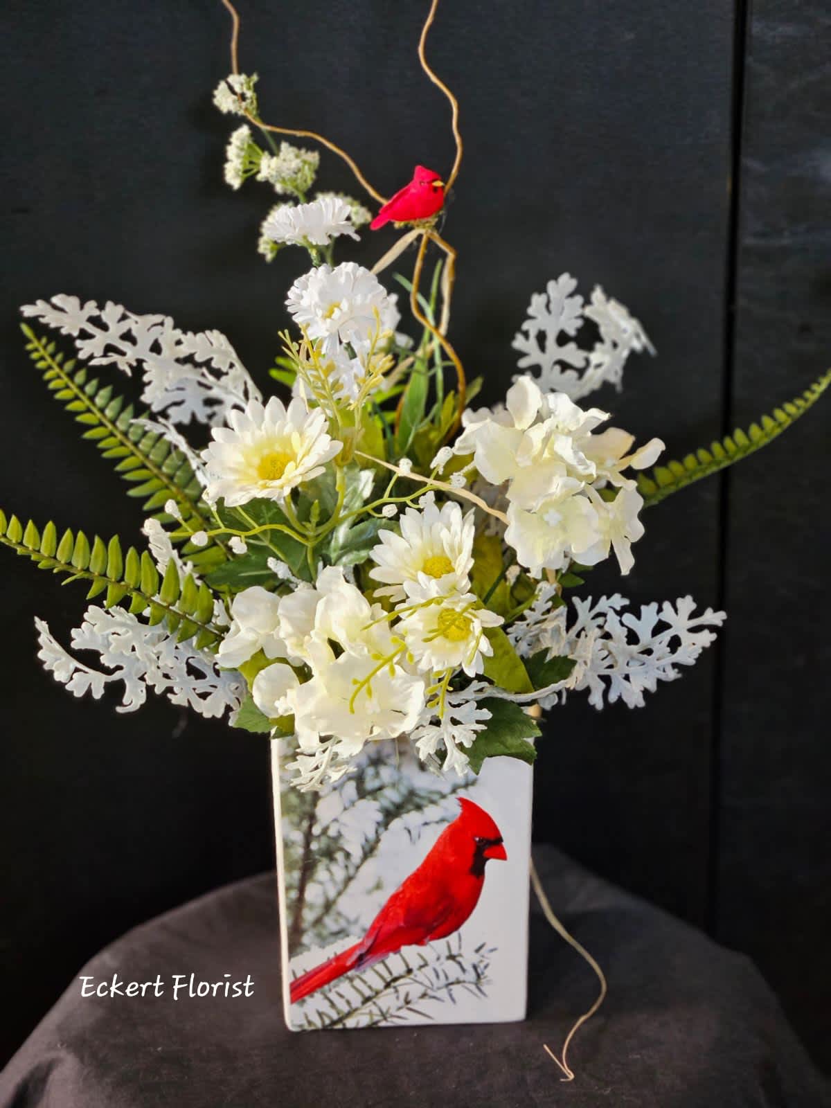Eckert Florist's Artificial Cardinal Bouquet  Eckert Florist's Artificial Cardinal Bouquet  - Artificial arrangement Ceramic container measures 6" H x 4.5" W x 3.5" Deep Total arrangement measures approx. 17" H x 19" W *Our Local Delivery Only