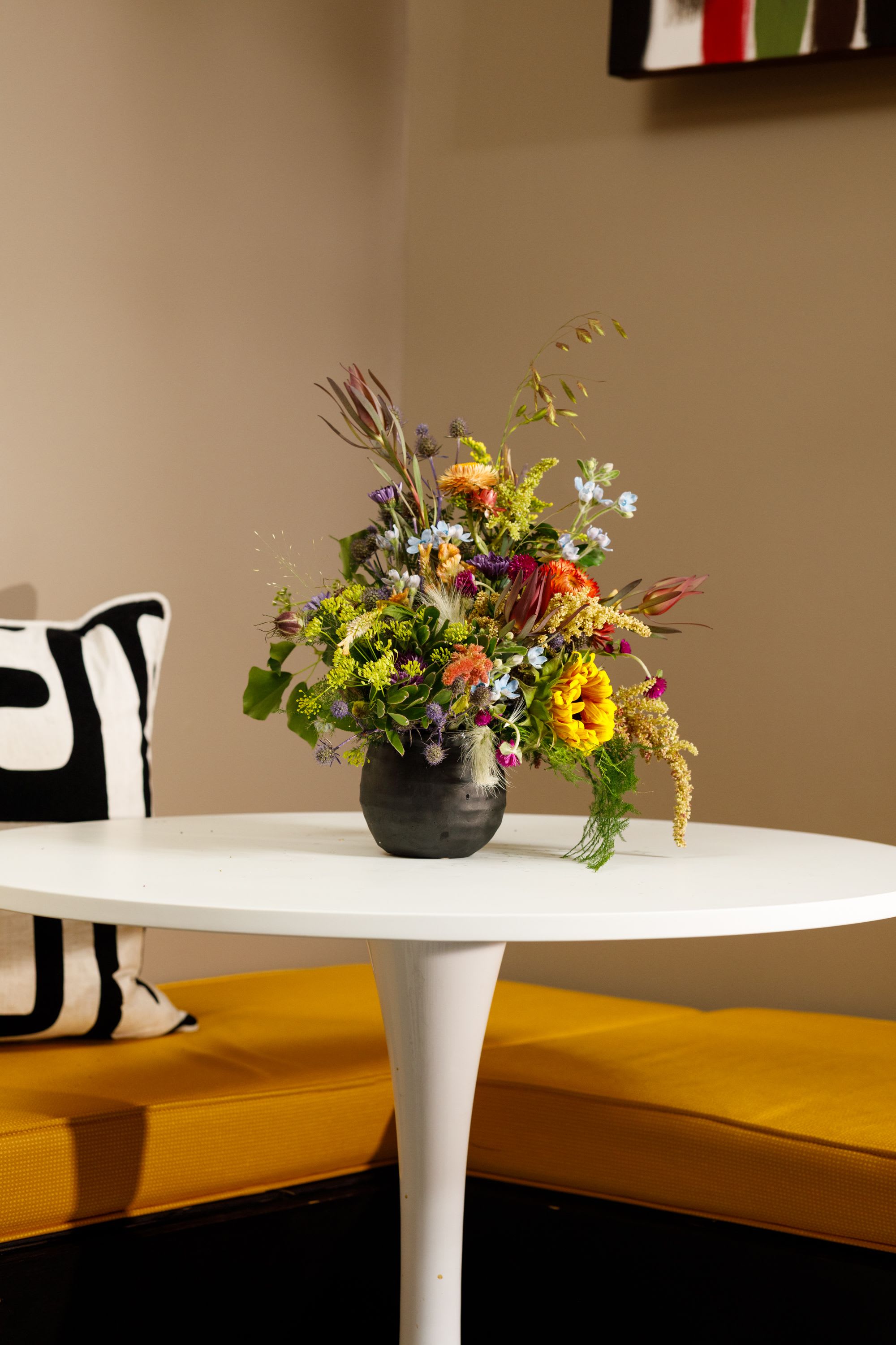 Bed-Stuy Collection: The Chauncey (For Him), Summer/Fall Edit  - Give him something unexpected and offbeat with this carefully curated arrangement “The Chancey” it is created with him in mind using bold textures, deep hues, and unique blooms for your husband, boyfriend, friend, or that special guy in your life.   Each of our custom designs is created using fresh curated seasonal blooms and foliages. Designers will choose from a unique array of flowers to create an arrangement tailored for you. For special floral requests please place order 4 days prior to the desired delivery date.   **Please note that Brooklyn Blooms move with the seasons, vessels, blooms, and foliage will vary from what you see in the photo. However, it will have the same beauty, uniqueness, and funky style. Please let us know in the florist notes if you have any color preferences, want to use photo as design inspiration or any special requests, otherwise, the Bloomies will make a tasteful decision for you! **  ***ALL SPECIAL REQUESTS MUST BE SPECIFIED IN THE FLORIST NOTES SO THAT OUR BLOOMIES ARE AWARE AND CAN DELIVER THE BEST SERVICE. COMMUNICATION IS KEY!!****  Upgrade Notes: Please note that with each upgrade the Bloomies will choose a mix of blooms, premium foliages, and filler to enhance your arrangement for the best presentation!  