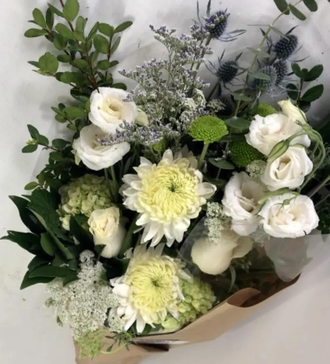 Hand-Tied Bouquet #8 Hand-Tied Bouquet #8 - A serene and elegant hand-tied bouquet in soft white and green tones, this bouquet features creamy chrysanthemums, delicate white lisianthus, and Queen Anne’s lace, complemented by sprigs of thistle and subtle blue-toned accents. A refined mix of textures and greenery brings a fresh, natural charm.