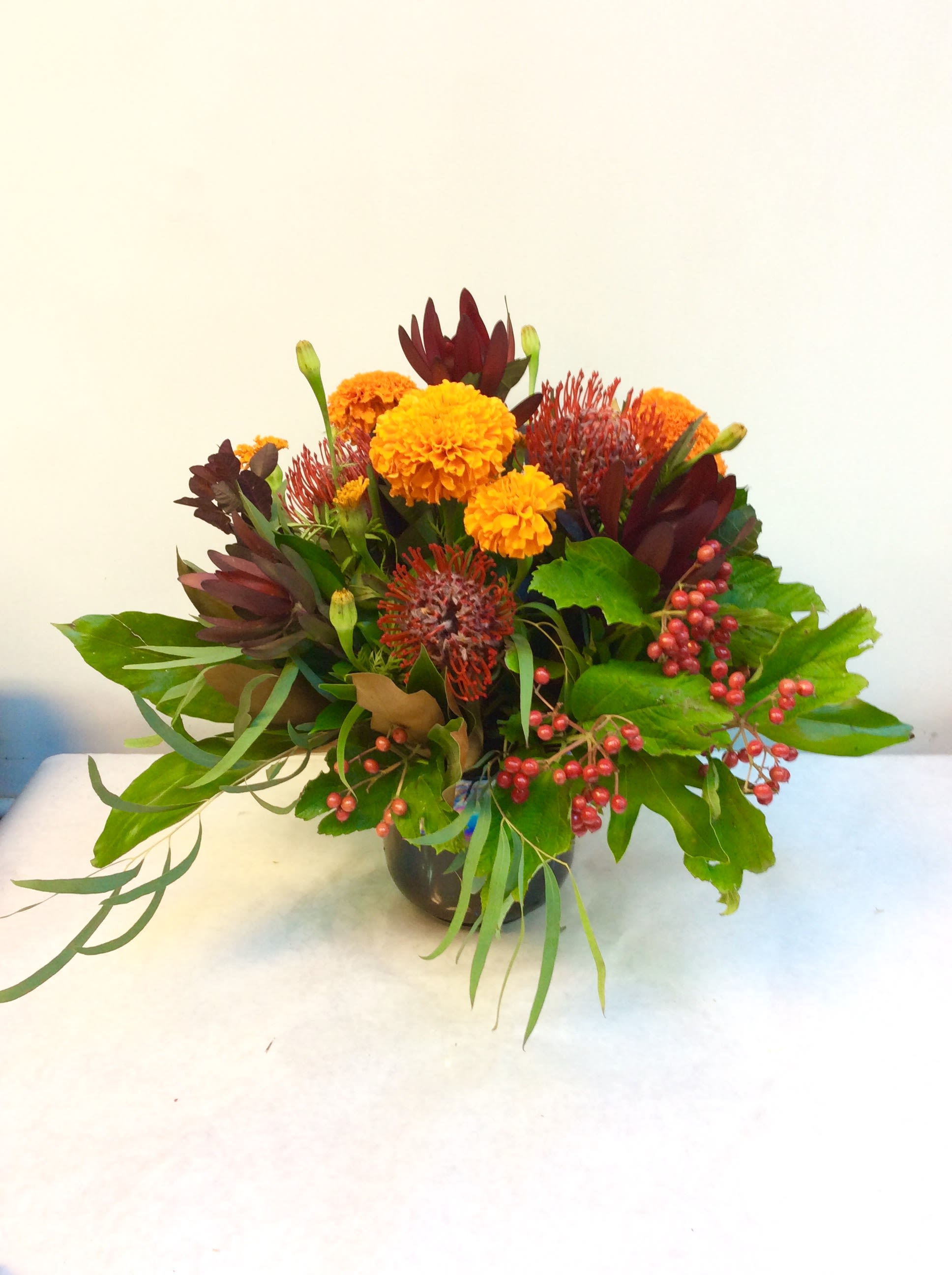 Autumn Bliss - Autumn texture galore!  Wonderful and longer lasting pin cushion protea, luecedendron, marigolds, astrantia and more in a beautiful brown cylinder vase.  HFS 201608-08