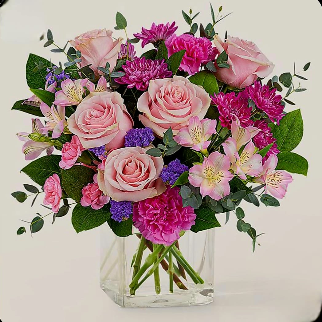 Golden Times by Pretty in Petal Golden Times by Pretty in Petal - This arrangement features a harmonious blend of soft and vibrant tones, anchored by light pink roses that offer a classic, romantic focal point. Surrounding them are magenta chrysanthemums, adding depth and texture with their dense, petal-packed form.