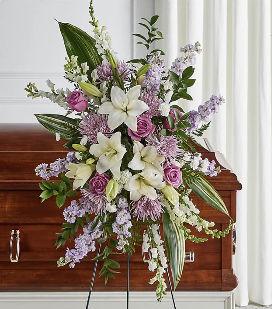 Lavender Blessings Lavender Blessings - Lavender and white flowers beautifully arranged on this easel piece, ensure your loved one knows just how much you care. Roses, lilies, daisys and mums.