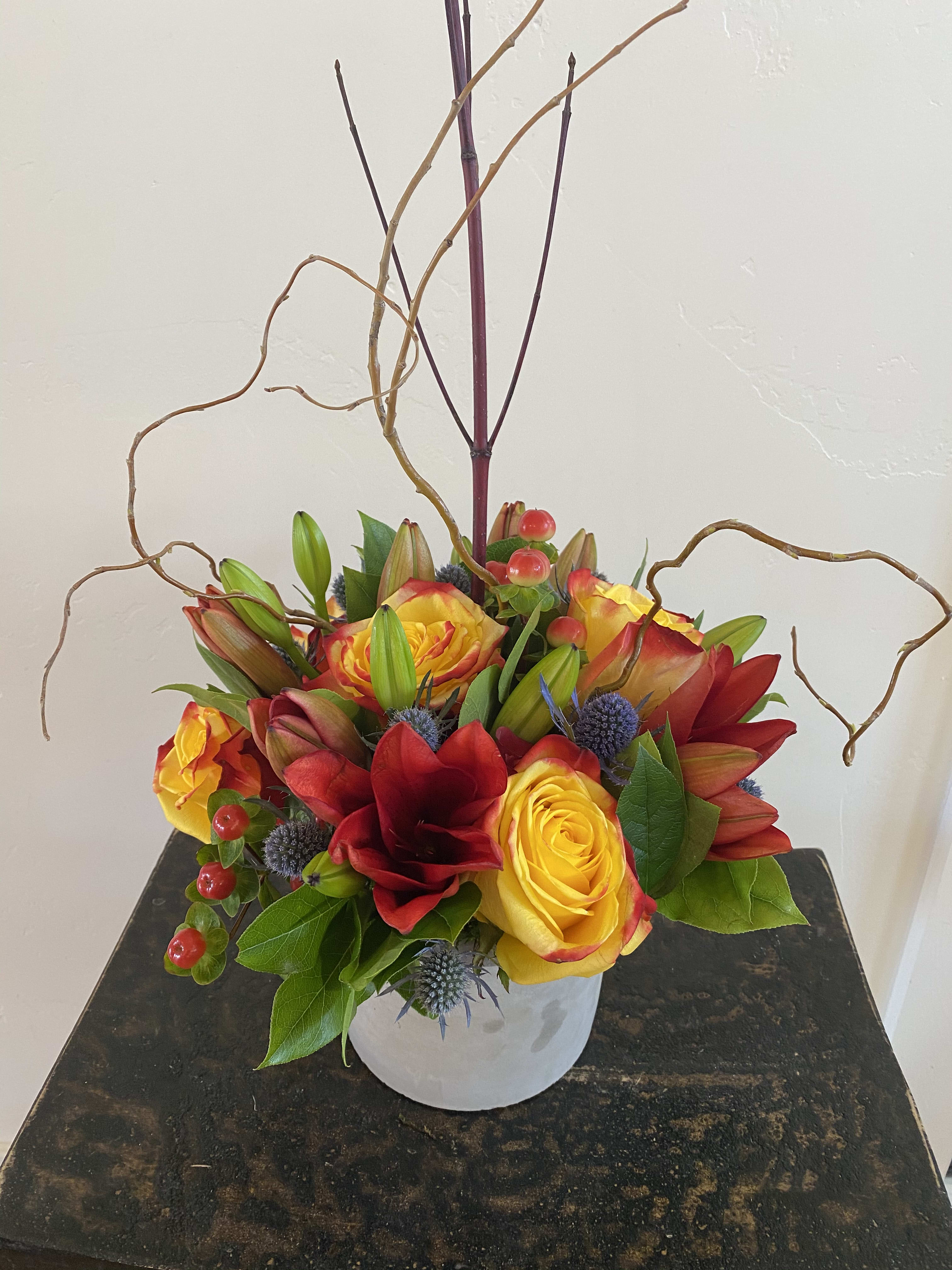 Harmony - A beautiful compact design of asiatic lilies, roses, hypericum, eryngium and more artfully designed in a ceramic vessel. Finished off with a flair of seasonal branches. 