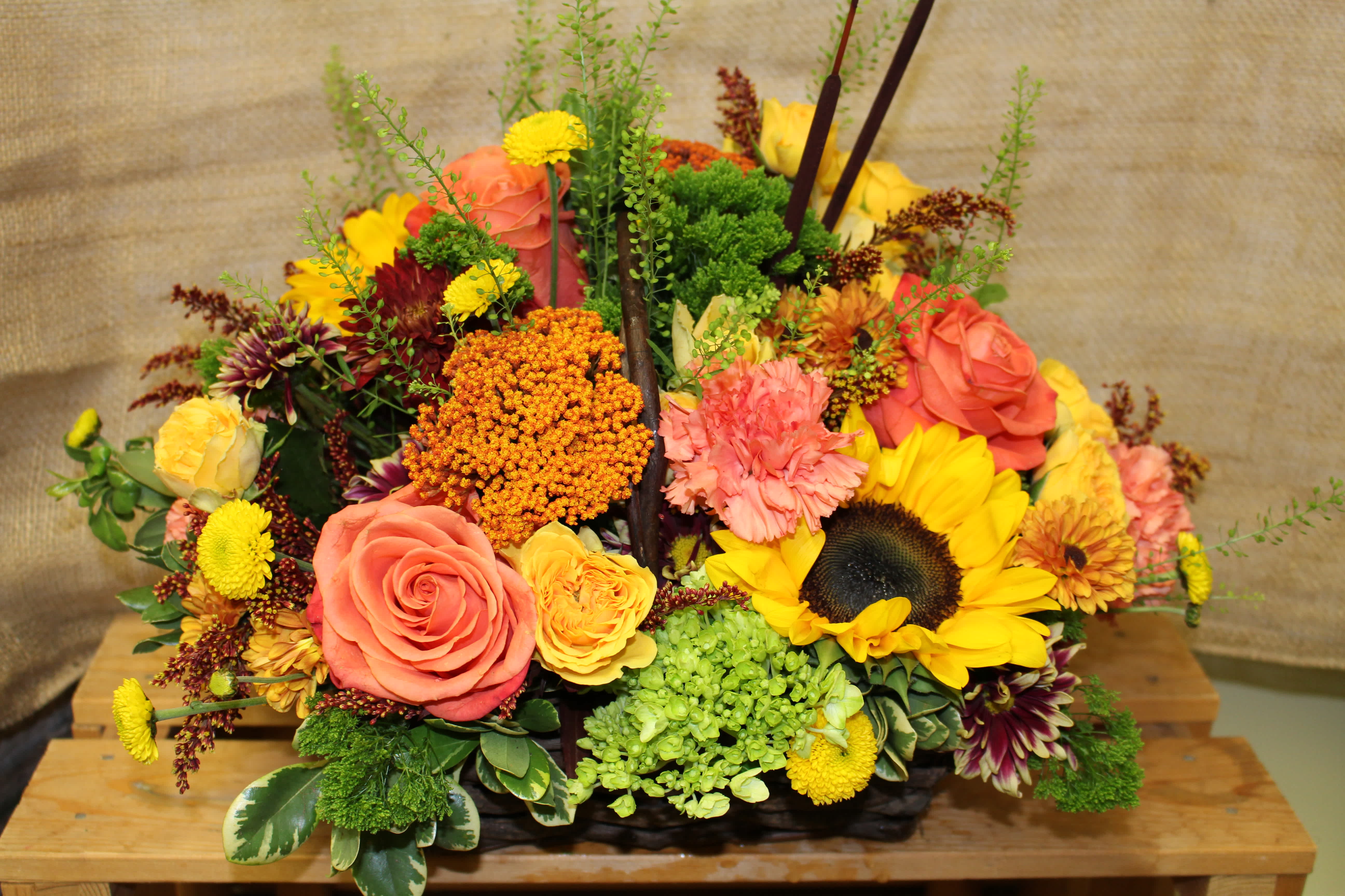 Autumn Basket Autumn Basket - Vibrant autumn arrangement in a rectangle willow basket with handle. Including roses, hydrangea, sunflowers and spray roses.