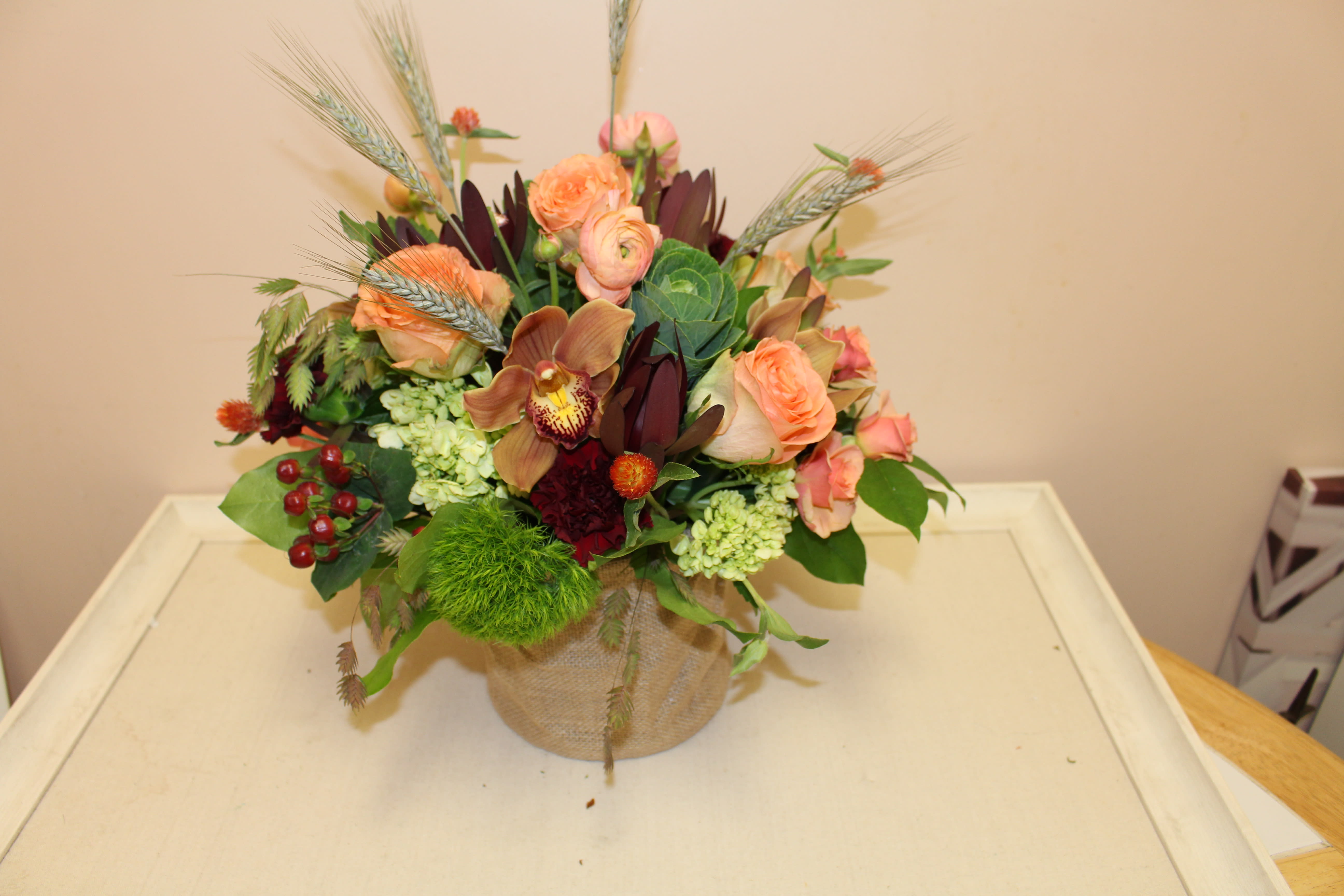 box of treasure - A chic burlap cylinder filled with cymbidium orchids, roses, hydrangea and other flowers.  a different take on your traditional centerpiece
