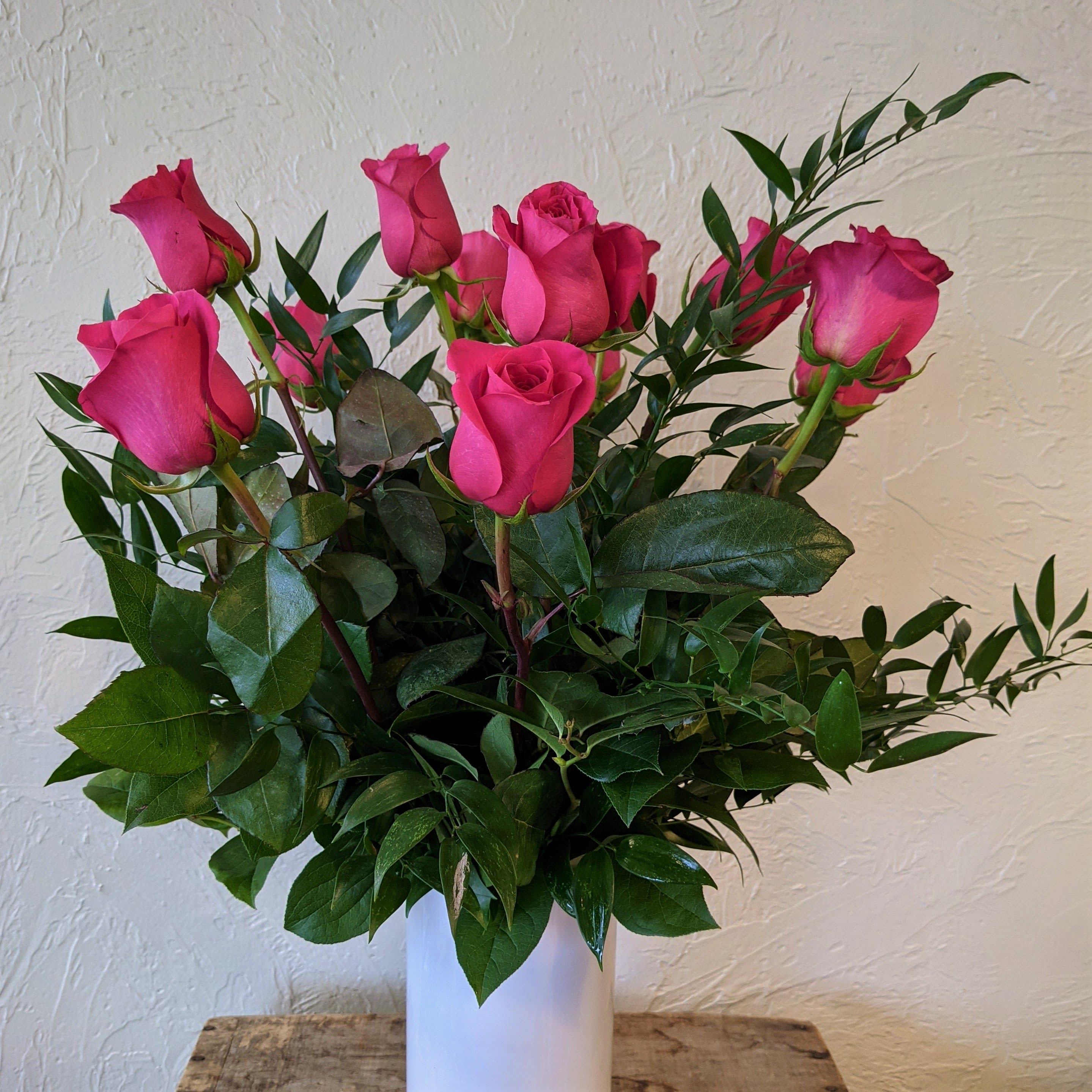 Pink Roses in a Vase - A timeless classic, send a dozen roses in a vase with complementing greenery. Also available in a dozen and a half and two dozen options, just select Deluxe or Premium respectively.