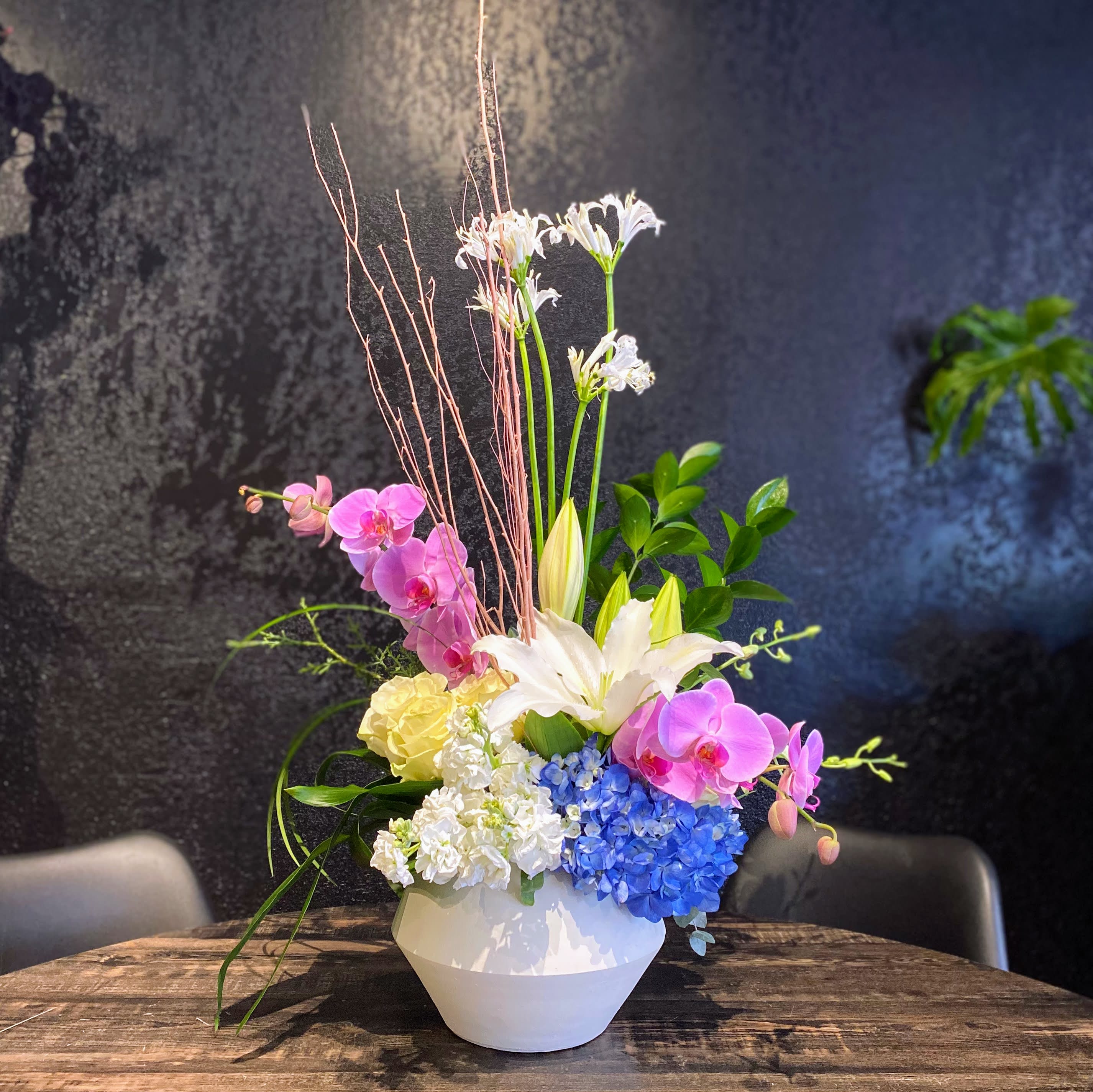 Brenda - Tall. Striking. Unique. Brenda. A contemporary design in our new favorite ceramic container that has a variety of flowers shooting upwards that can turn heads from across the room. Container measures roughly 10x10&quot;