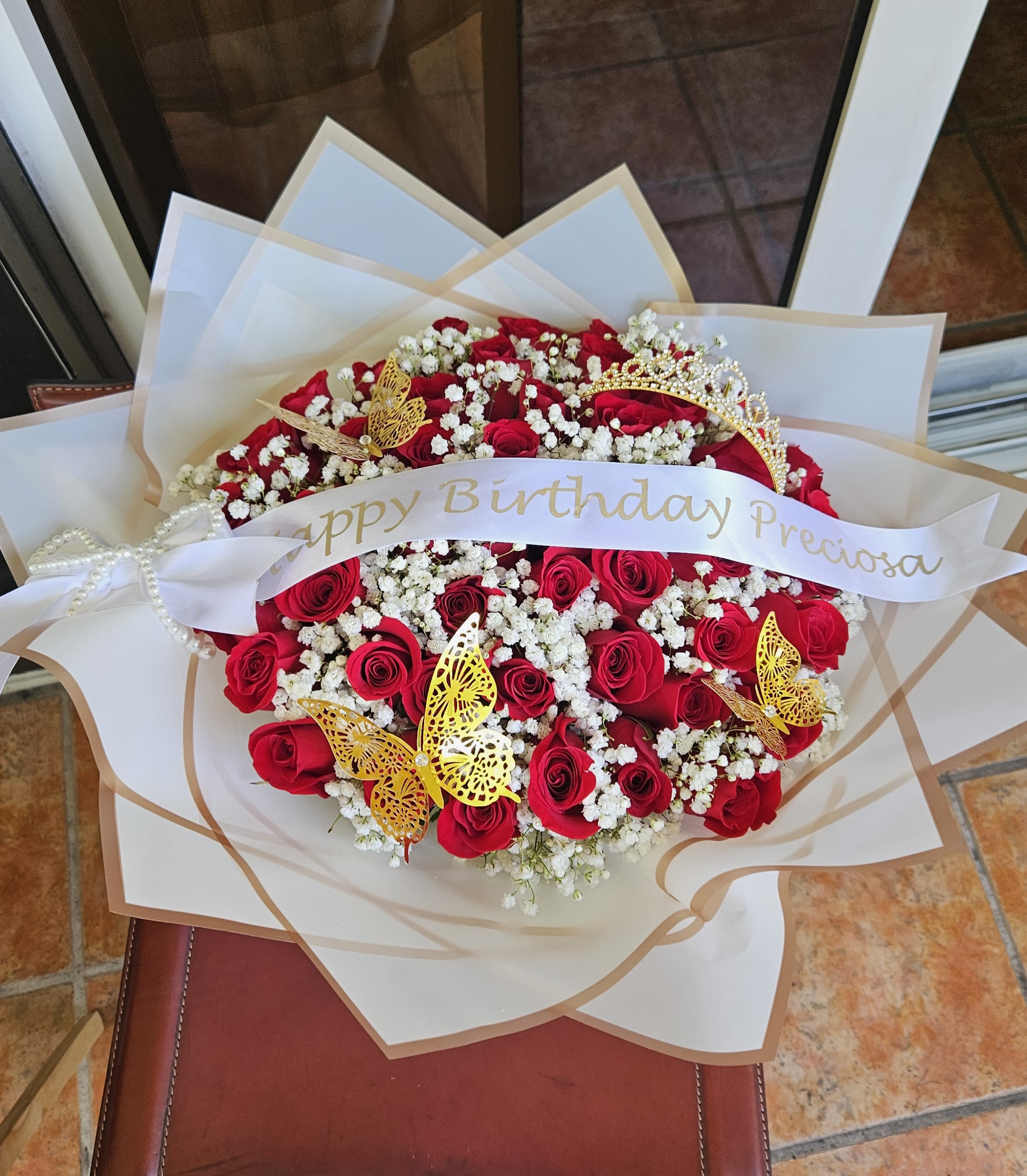 Ramo de Rosas &quot;Preciosa&quot;  - Celebra un día especial con nuestro exclusivo ramo &quot;Preciosa&quot;, diseñado para impresionar. Este lujoso arreglo floral presenta una abundante colección de rosas rojas frescas, delicadamente combinadas con flores de relleno blancas que añaden un toque de elegancia. Adornado con detalles dorados, incluyendo mariposas y una corona, este ramo está envuelto en un elegante papel blanco con un lazo de satén. Una cinta personalizada con la inscripción &quot;Happy Birthday Preciosa&quot; en letras doradas completa este regalo único, ideal para expresar amor y aprecio. Perfecto para sorprender a esa persona especial en su día especial.  - Flores: Rosas rojas, flores de relleno blancas, (puede perzonalizar en cualquier color) - Decoración: Mariposas y corona doradas, lazo de satén, cinta personalizada. - Papel blanco de alta calidad (también puede perzonalizarlo) - Ocasión: Cumpleaños, aniversarios, regalos sorpresa.