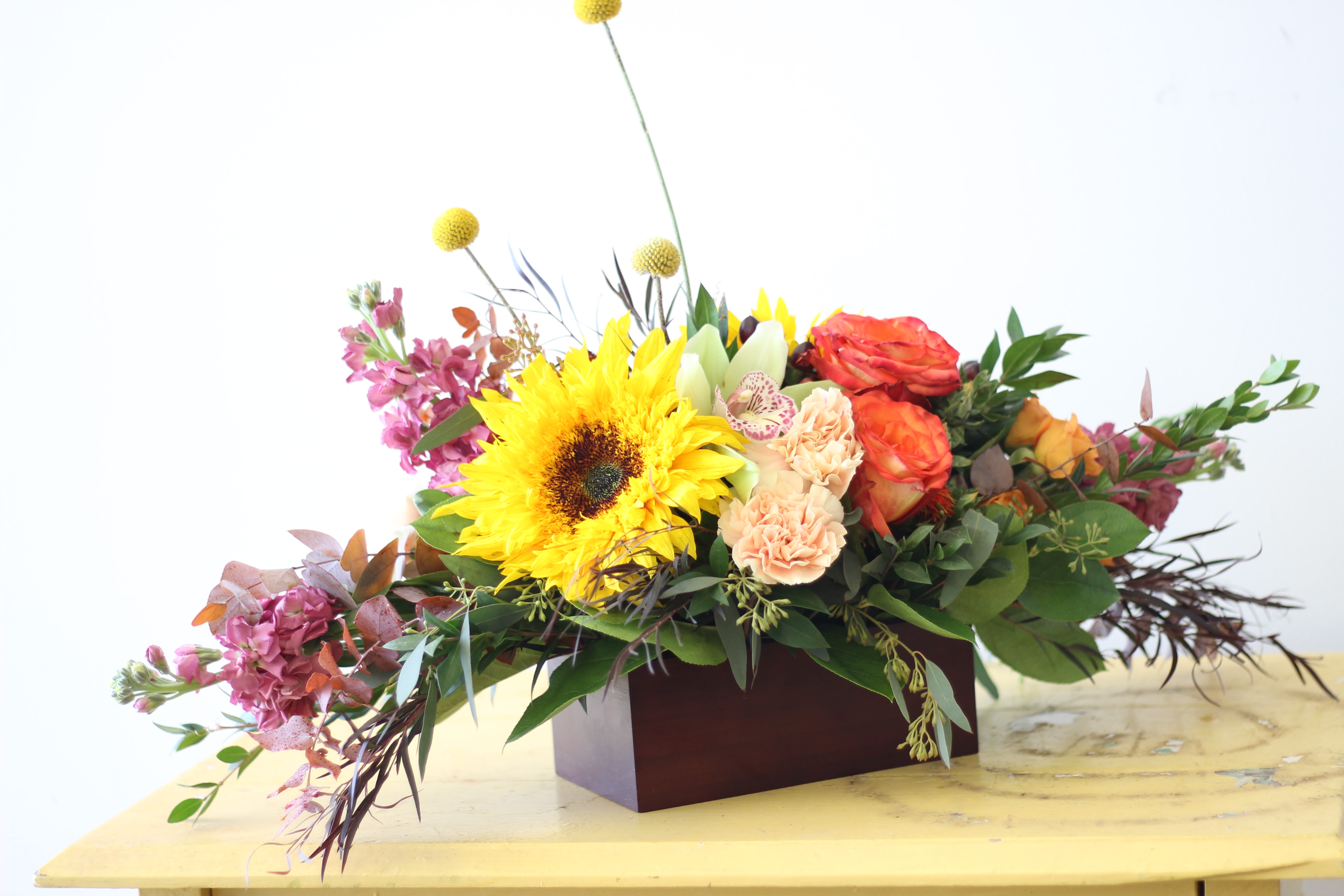 Pale September - Send this beautiful display of signature autumn blooms as the seasons change, and usher in the cooler days ahead. This piece is handcrafted in a wooden vessel and while the seasonal accents and textures may vary from piece to piece, the spirit of the design will remain. 