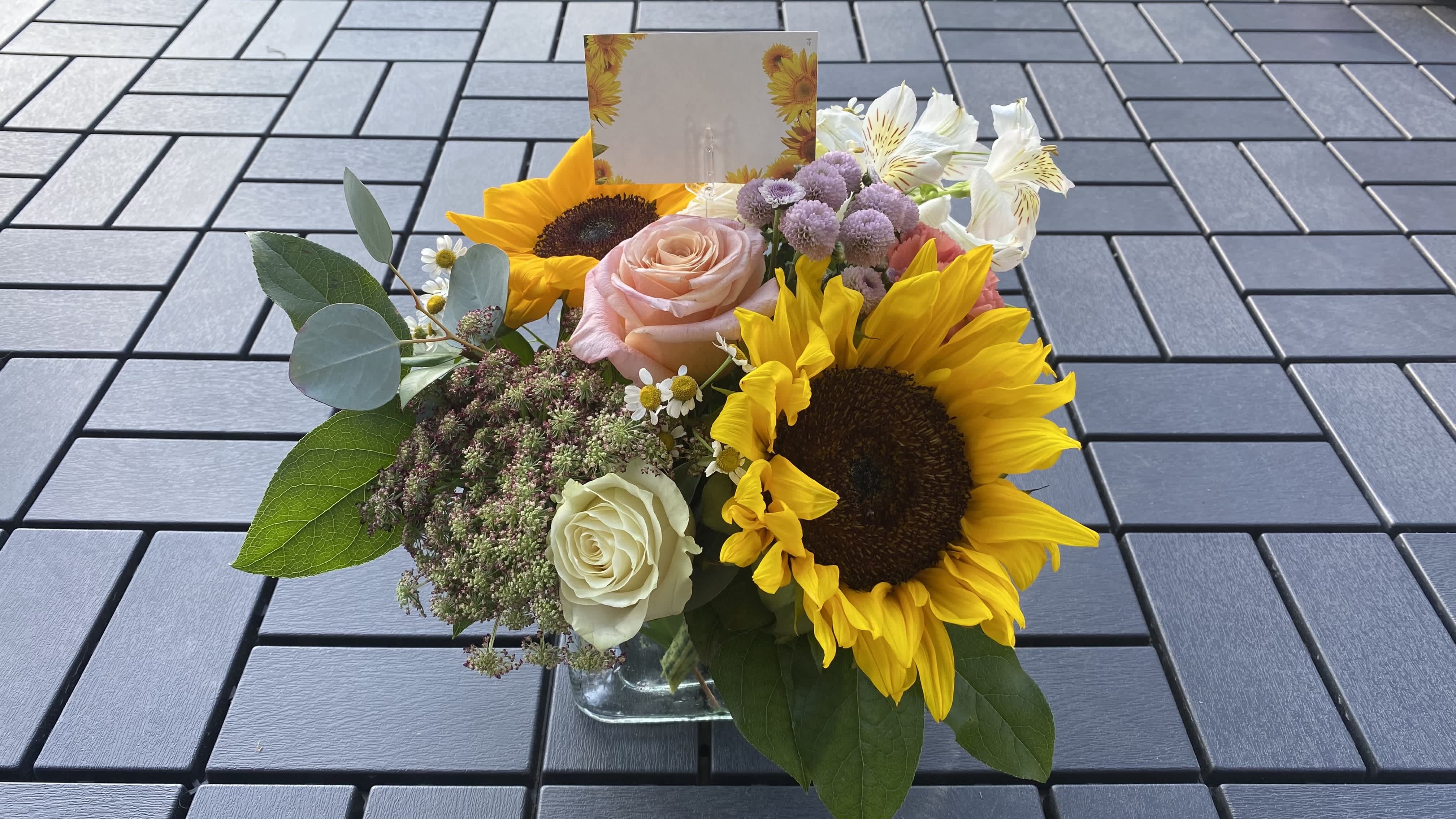 Cube: Fresh Meadows Cube: Fresh Meadows - Dimension: 9.5”H x 10”W Flowers: Roses ,Sunflowers, Alstroemerias , Fancy Carnations and other seasonal flowers. Material: 5”H Modern Cube Vase Flowers & Fillers may vary depend Available. And will be delivered approximately as pictured.