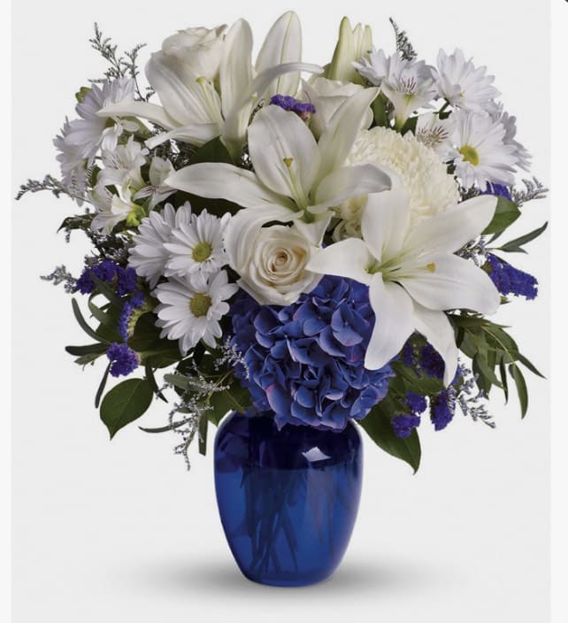 Blue &amp; White Arrangement  - Blue Hydrangea, White lilies, Cream Roses, Blue Delphinium, White Chrysanthemums and Greens, Limonium, Bupleurum, White Alstroemerias, Purple Statice, Cobalt Vase Approximate measurements: 18H Standard and Deluxe sizes: Blue Cobalt Vase 8” H Premium size: Blue Cobalt vase 10 3/4&quot; H