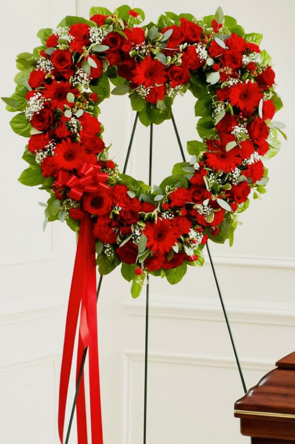 RED STANDING OPEN HEART - RED STANDING OPEN HEART with Red roses, Gerberas daisies, alstroemerias, carnations, spray roses, Leather leaf, Baby’s breath, Tree Fern, Red ribbon. 