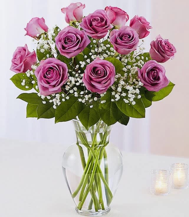  Explosion of Lavender Roses - Lavender Roses with Limonium and seasonal greens in Clear vase 8” H Standard 12 roses Deluxe 18 roses  Premium 24 roses and 10 3/4” H Clear vase 