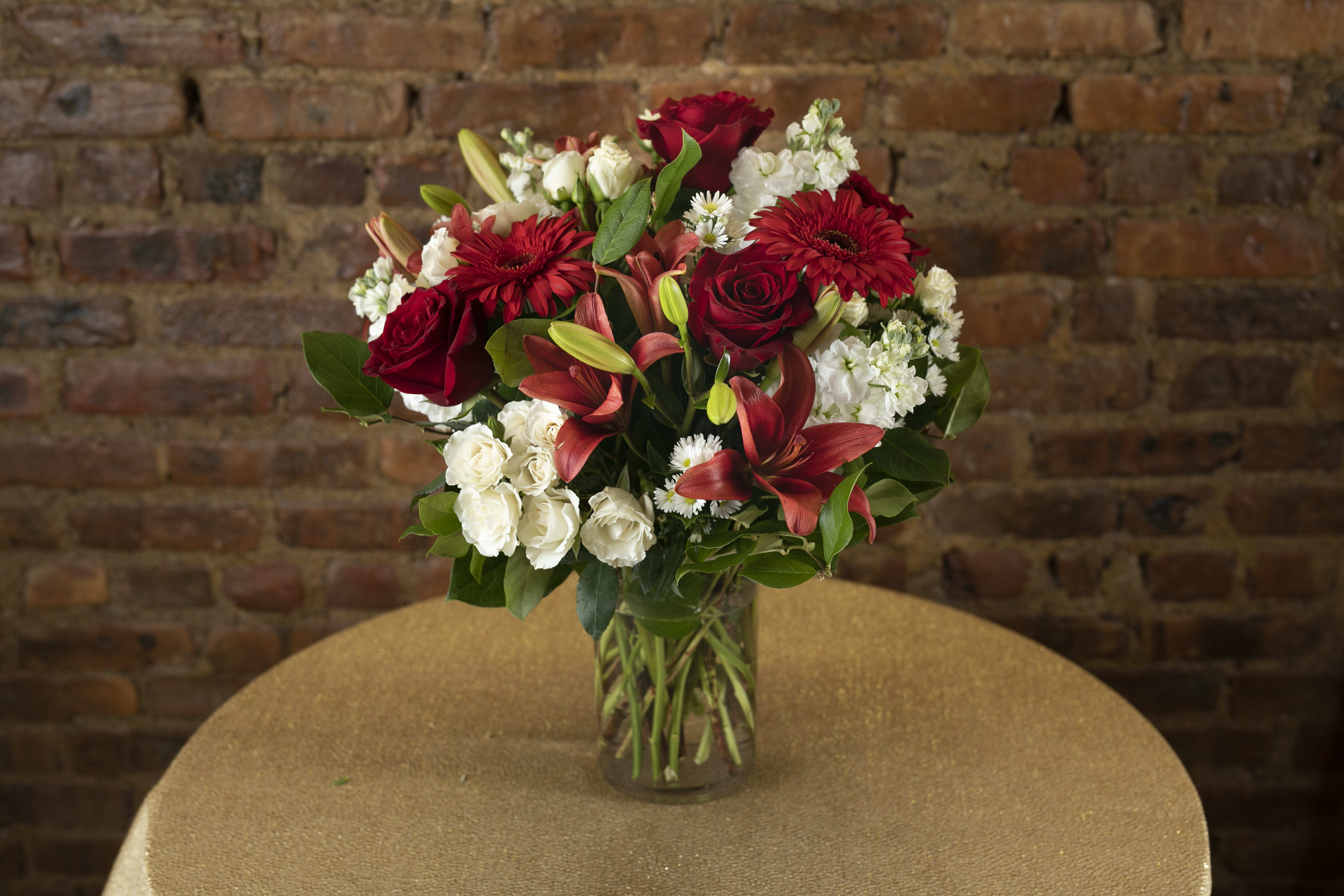 Red and White Blossoms  - A gorgeous display red and white toned seasonal floral blooms designed in a decadent glass  cylinder vessel.  Orientation: All-Around All prices in USD ($) Standard, Deluxe (Shown), Premium