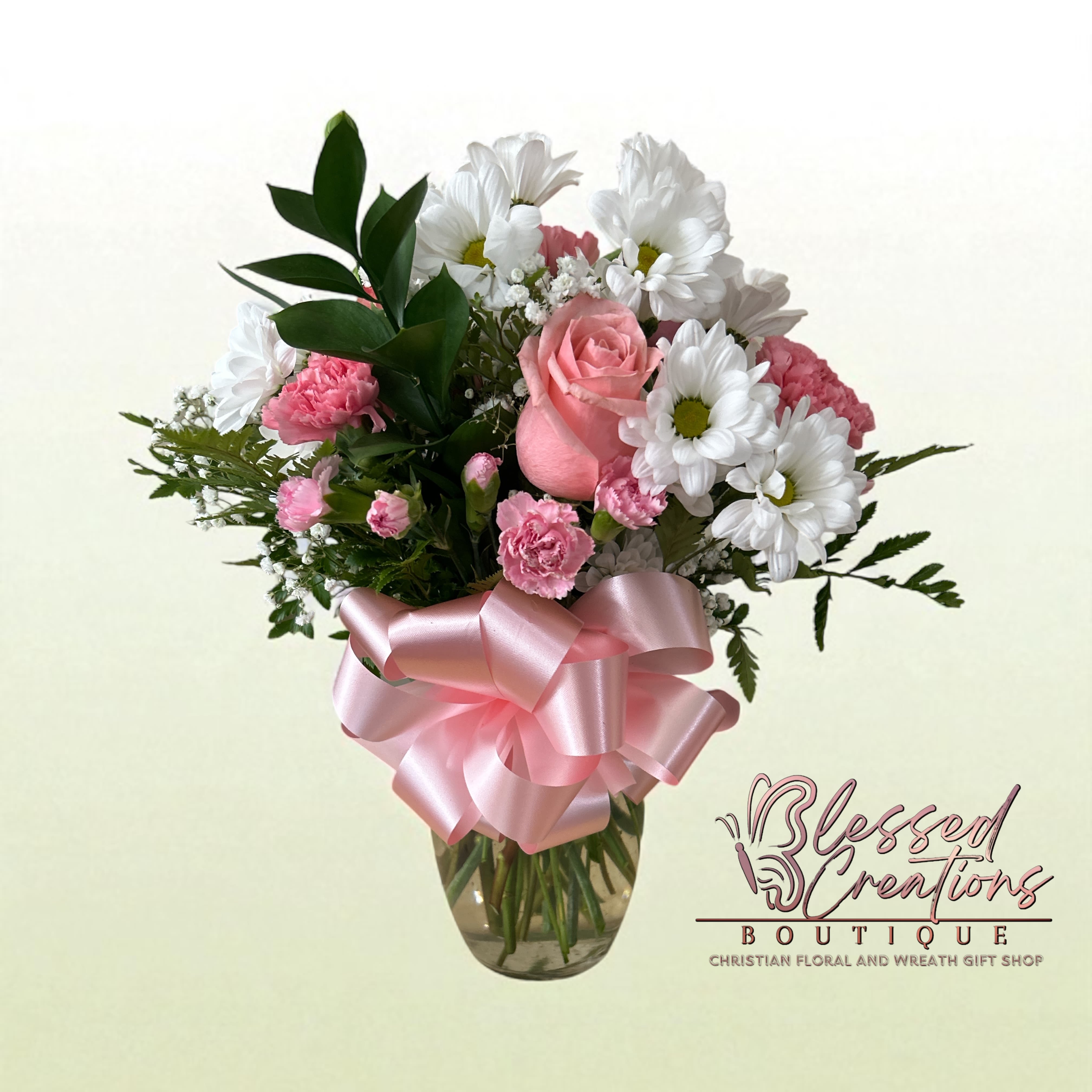 Sweet Grace Vase  - Delicate and full of charm, this arrangement features soft pink roses, pink carnations, white daisies, baby’s breath, and lush greenery, gathered in a clear vase and adorned with a satin pink bow. A tender design that radiates sweetness and love—perfect for birthdays, encouragement, new baby celebrations, or simply to brighten someone’s day.