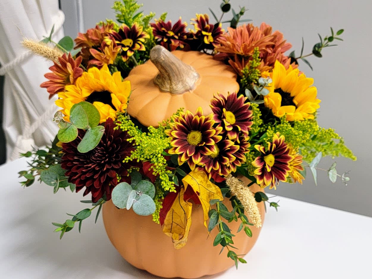 Fall Floral Ceramic Pumpkin  - A beautiful assortment of fall tones elegantly arranged in a keepsake ceramic pumpkin with lid.  Flowers include long lasting flowers such as mums and sunflowers accented with colorful foliage  and asters. Standard size is shown. 