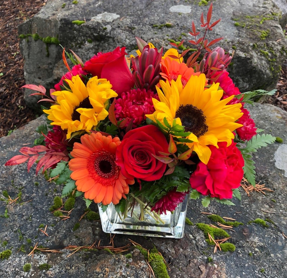 Sunset Skies Sunset Skies - Bright yellow, hot pink and orange. Vibrant and oh so beautiful. This arrangement has sunflowers, roses, gerbras, and other fall flowers.