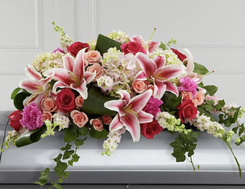 Splendid Grace Casket Spray - Splendid Grace Casket Spray is a special way for honoring lost loved ones. It features a beautiful fusion of roses, larkspur, hydrangeas, carnations and lilies accented with a variety of lush greens including ivy vines and aspidistra. Made to fit the closed top of the casket, it is ideal for display on caskets at funeral homes or graveside. 