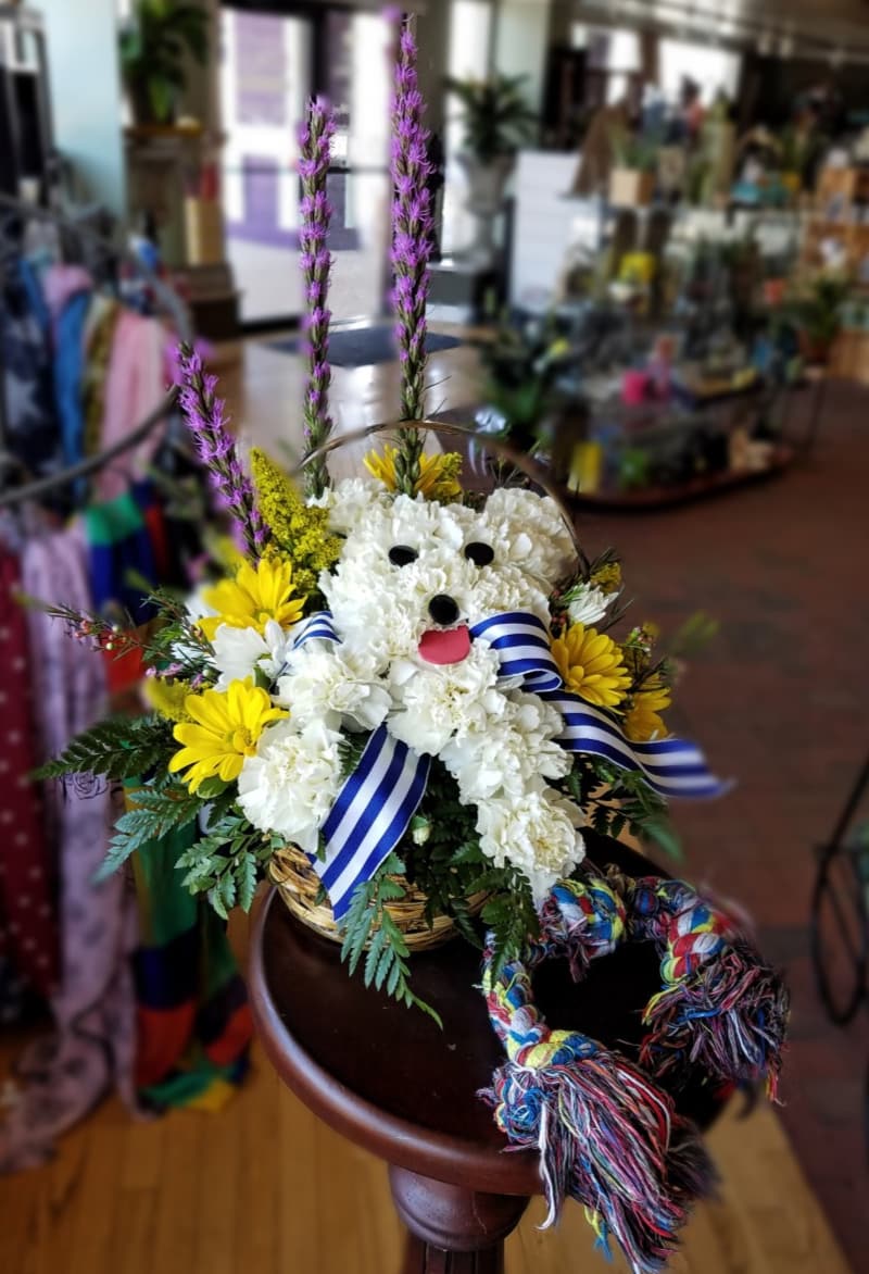 Dog Gone Cute - This cute arrangement is a pup in a basket made of flowers! Everyone wants to get a puppy gifted to them but it's not always a good idea, and you can only get so many before you run out of space! This basket lets you give that puppy but without all the commitment.  Ribbons may vary. Made in an approx. 6 inch basket