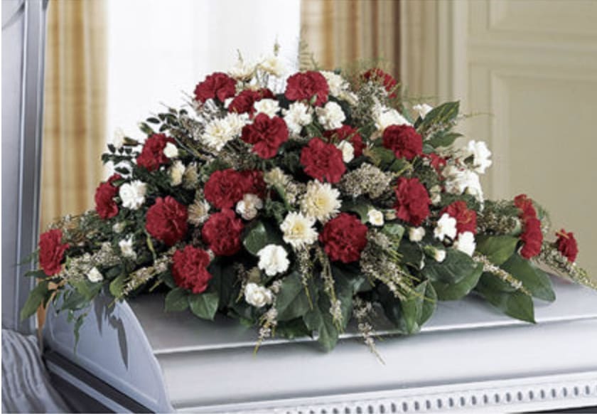 Forever in Our Hearts Casket Spray - A classic red and white casket spray symbolizing devotion and respect. Crafted with red carnations, white poms, and lush greenery to honor a life deeply cherished.