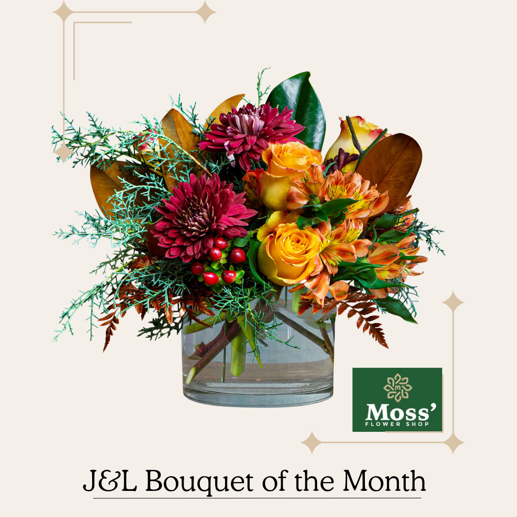 Fall Deco Bouquet  - A clear glass container with blooms in rusty tones of burgundy, orange, and copper. Roses, garden mums and alstroemerias give blasts of color among green foliage.