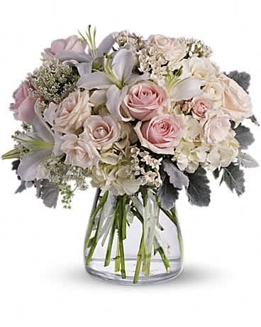 Beautiful Whisper Beautiful Whisper - A whisper-quiet affirmation of love. Subtle shadings of pink and white roses, lilies and delicate Queen Anne's lace in a simple, elegant vase. Gorgeous flowers such as white, crème and light pink roses, white oriental lilies and delicate Queen Anne's lace with a touch of silvery dusty miller, all in a classic hurricane vase.
