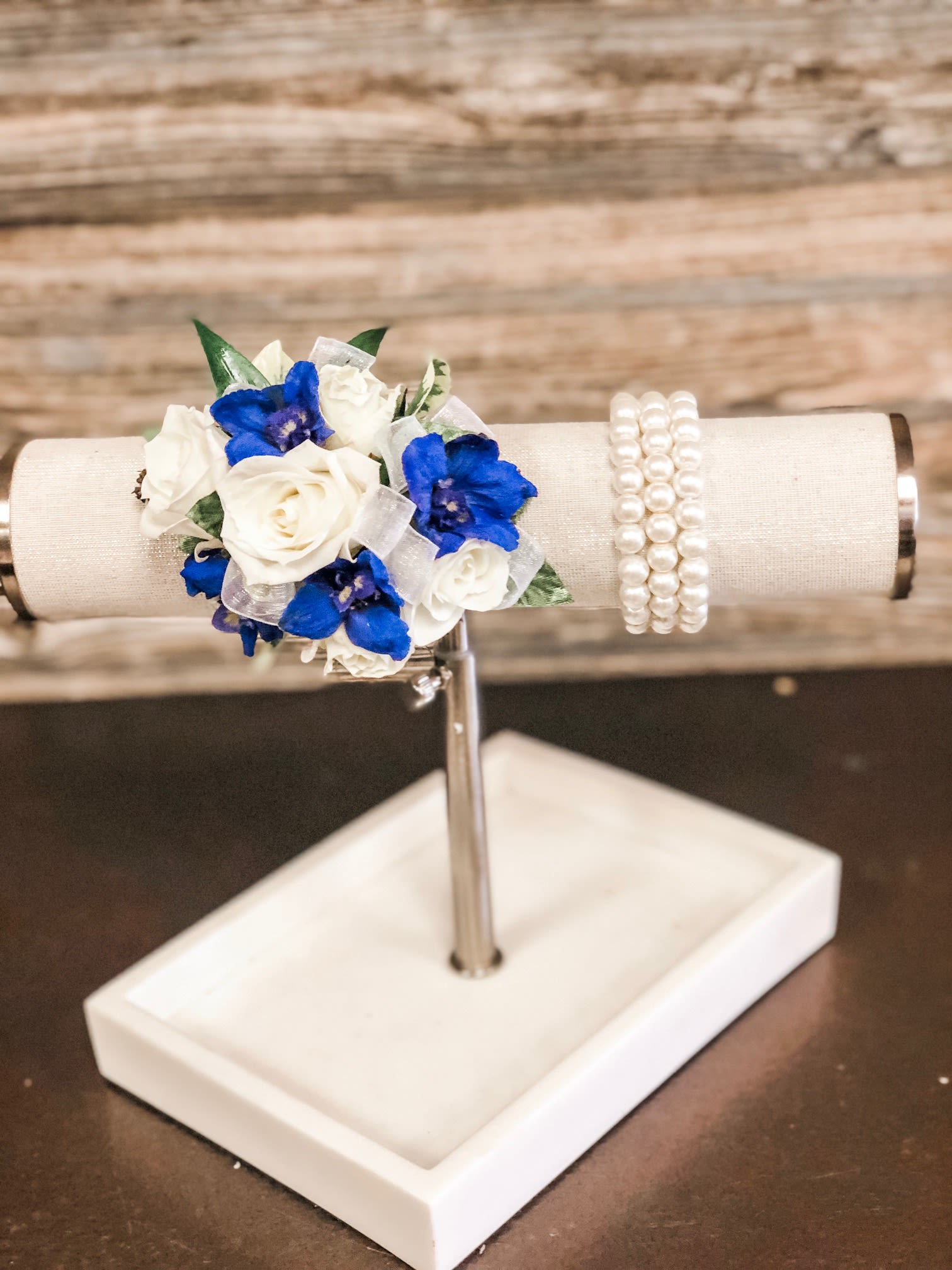White Spray Rose and Blue Delphinium Corsage with Upgraded Wristlet - White spray roses, sheer ribbon, blue delphinium on a bed of greenery.  Wristlet and ribbon color can be customized.   Ribbon:  can match or compliment any dress color Wristlet:  white faux pearl. 