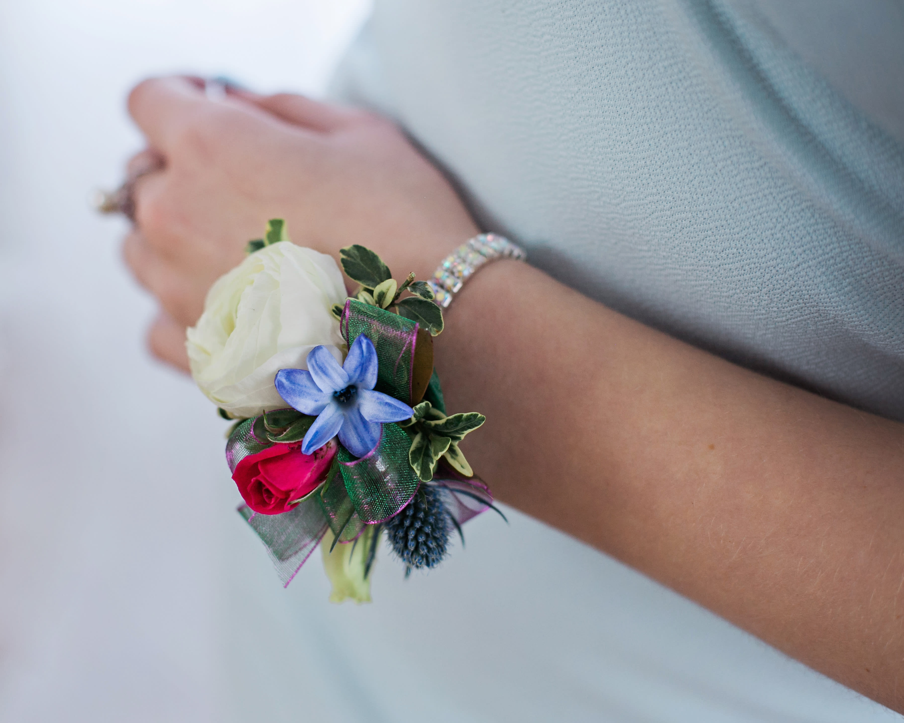 Rhinestone corsage with mixed blooms - Pick Up Only Rhinestone corsage with mixed blooms - Pick Up Only - This rhinestone corsage features mixed blooms such as ranunculus, spray roses, blue thistle, blue hyacinth, and a tiny succulent bloom. The design is finished with foliage and ribbon. Tells us the dress color and we can suggest flower and ribbon colors to match. Ranunculus and spray rose color options - white, red, pink, coral, purple, orange and yellow. *please note that ALL corsages and boutonnieres are NON-REFUNDABLE after being made.