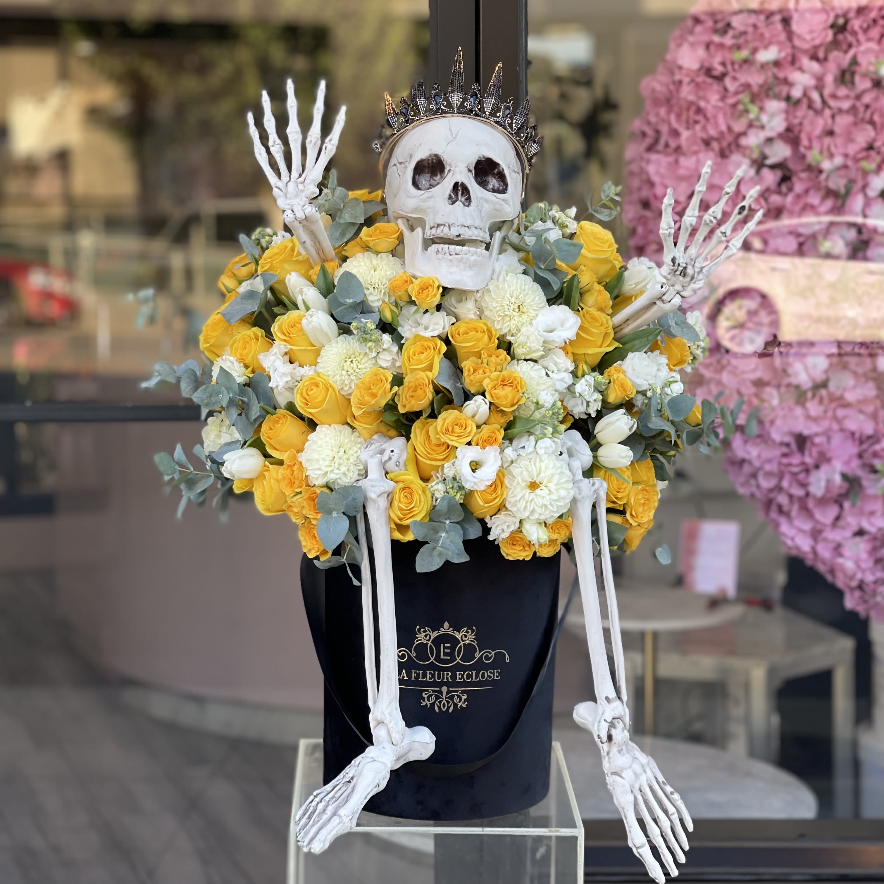 High five, Skeleton! - Arrangement of fresh yellow and white flowers with some greenery in between in our signature velvet black box with the skeleton 