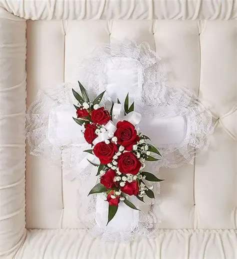 Cross shaped satin pillow Cross shaped satin pillow - Cross-shaped satin casket pillow is adorned with a spray of red roses and mini carnations with accents of , baby’s breath, ribbon and soft, lush greenery. This particular style of tribute is often sent by children or grandchildren and delivered directly to the funeral home.
