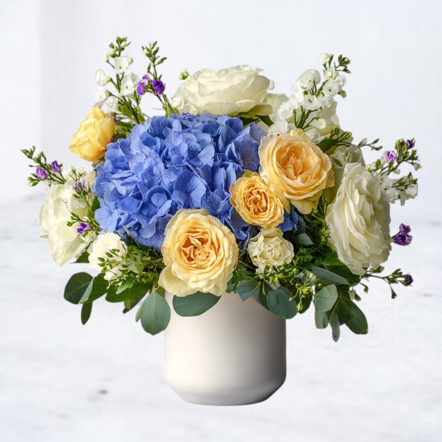 Blue Skies &amp; Sunshine - Bright, uplifting, and full of charm, our Blue Skies &amp; Sunshine Bouquet is designed to bring joy to any occasion. Featuring bold blue hydrangea paired with golden yellow garden roses, creamy white roses, and delicate pops of lavender accents, this arrangement balances cool serenity with warm radiance.  Hand-arranged in a modern white vase, it’s the perfect gift for birthdays, thank-you gestures, get-well wishes, or simply reminding someone they’re in your thoughts. The fresh, airy palette evokes the beauty of a clear sky at sunrise, making it a versatile choice year-round.  Best for: Birthdays Get Well Soon Thinking of You Thank You  Available for same-day delivery in Magnolia, The Woodlands, Spring, Conroe, Cypress, Tomball, and surrounding Houston-area cities.