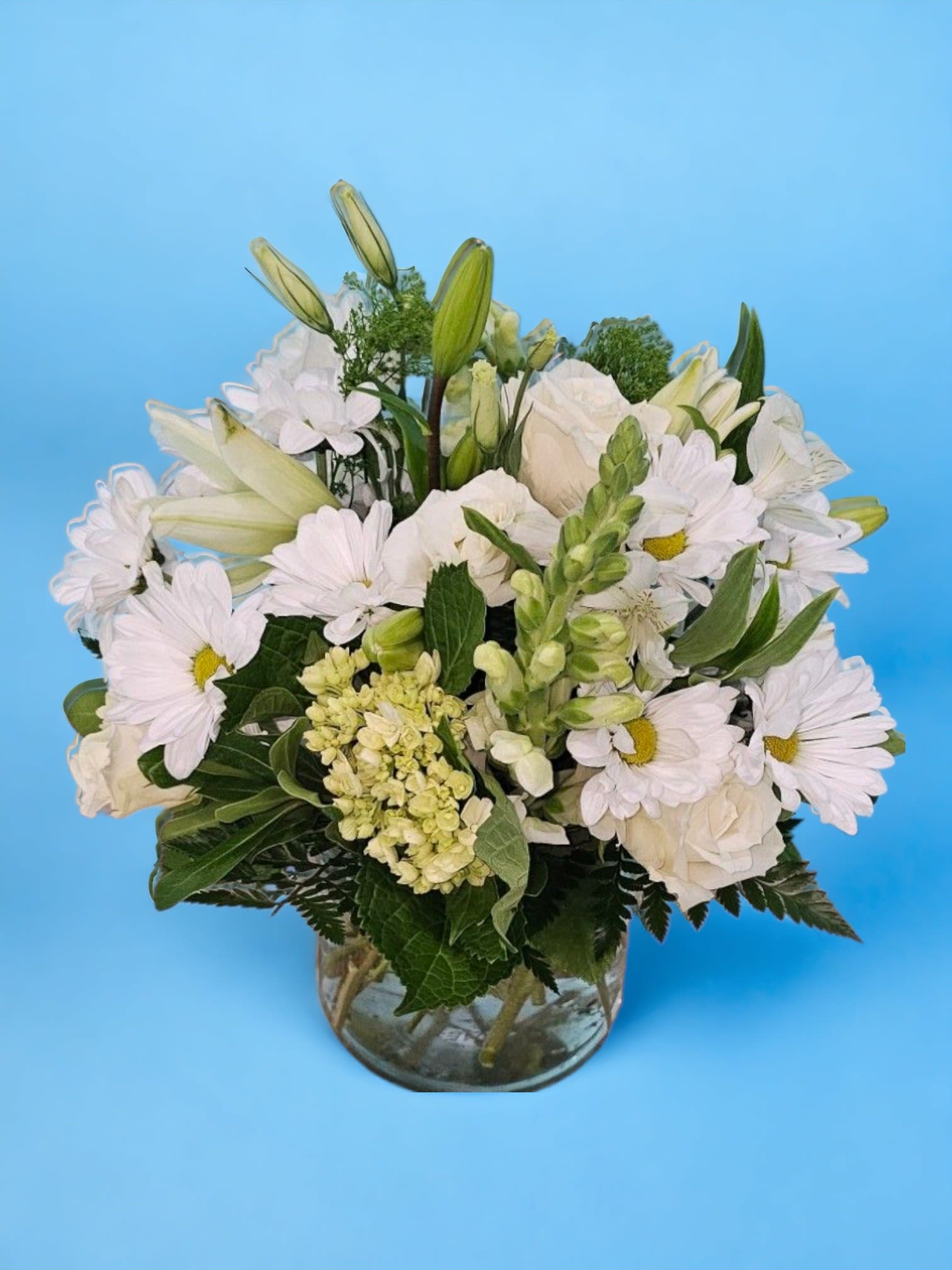 Whispering Tranquility - This arrangement convey a sense of freshness and elegance, highlighting the serene and cohesive nature of the white and green floral arrangement. An arrangement featuring white daisies, white snapdragons, white roses, white lilies, baby green hydrangeas, green trick, filler, and greenery