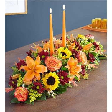 Fields Of Europe For Fall Centerpiece Fields Of Europe For Fall Centerpiece - The rich beauty of the European countryside comes alive in our best-selling fall centerpiece. Crafted by our artisan florists, it’s filled with a gathering of fresh-picked blooms in brilliant colors and finished with an orange candle to warm hearts and homes. • All-around centerpiece arrangement with autumn-colored roses, sunflowers, red daisy poms, orange Asiatic lilies, mini carnations and solidago;