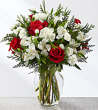 Walking In A Winter Wonderland Walking In A Winter Wonderland - This bouquet is crisp, cool, and blooms with the magic of the winter season to create an incredible holiday gift. Rich red roses and carnations make you take that second look, arranged throughout a bed of white Peruvian Lilies, carnations, and mini carnations, accented beautifully with an assortment of lush and fragrant holiday greens. Presented in a clear glass vase, this stunning holiday flower arrangement is that perfect Christmas, winter birthday, or thank you gift you've been searching for!