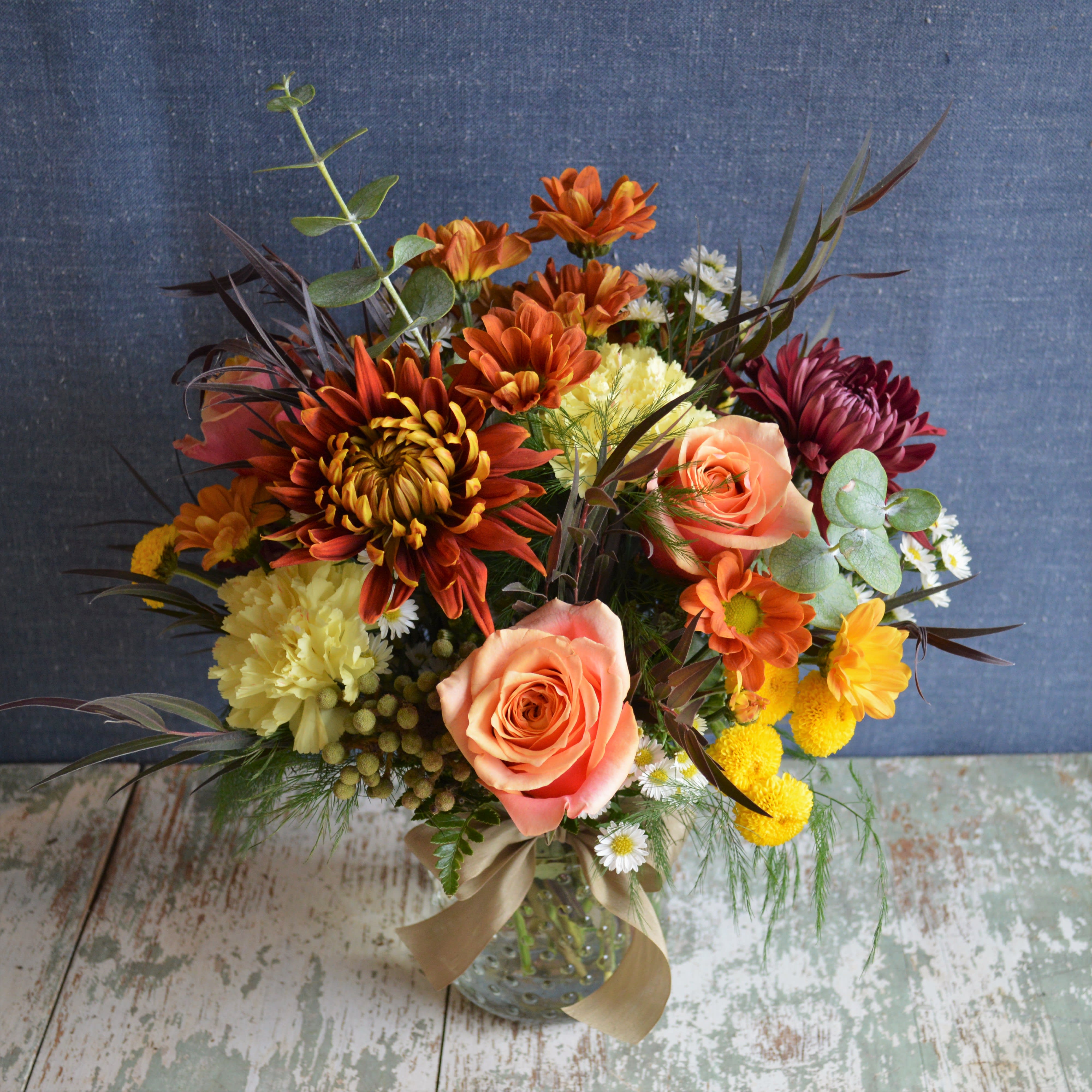 Maria Maria - Fresh fall flowers in a cylinder vase. Approximatley 15" tall x 10" wide.