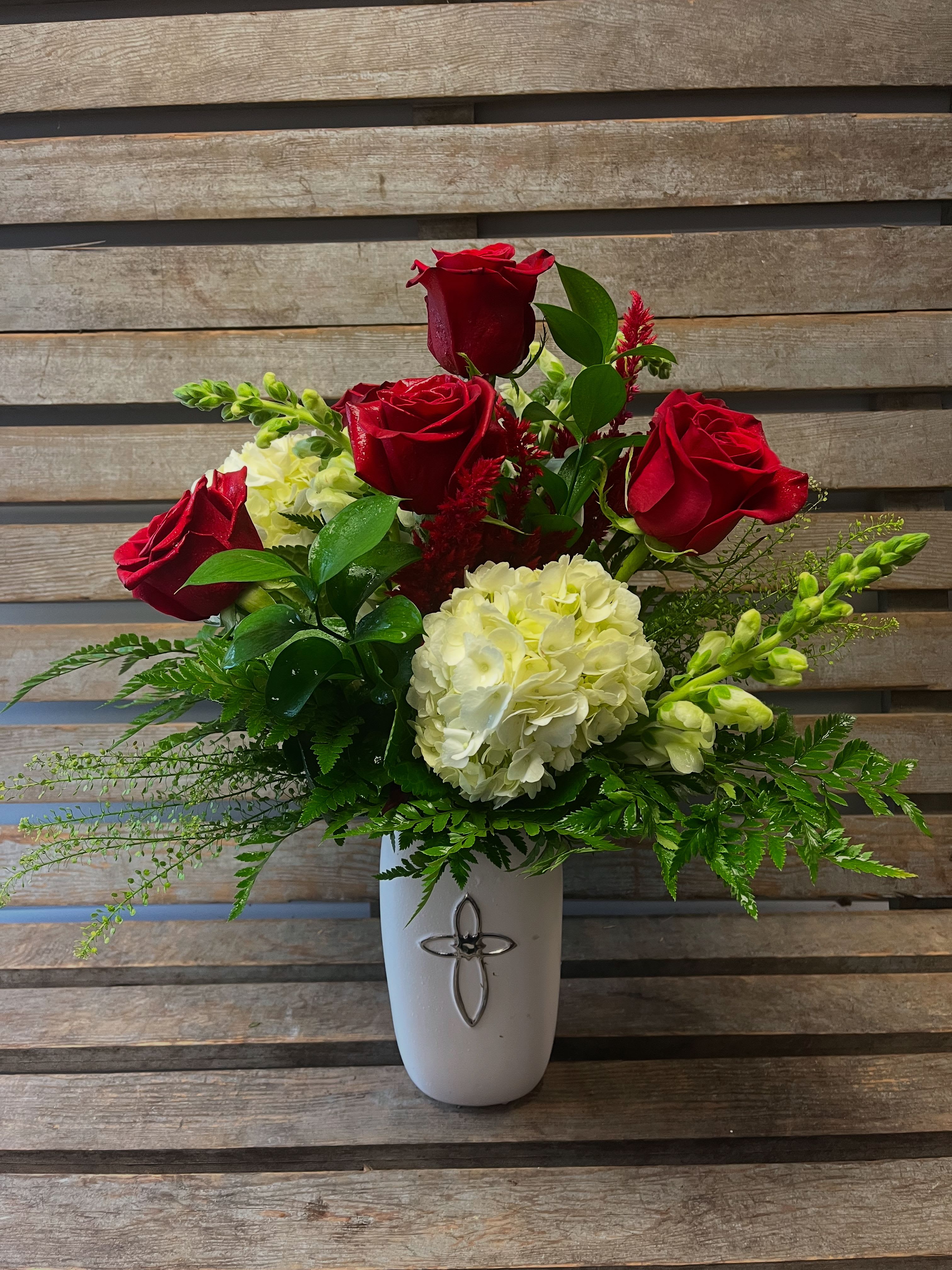 Sympathy and love red and white eternal cross vase  - Red roses , white hydrangea , snap dragons or stock with coordinating filler In a white ceramic vase with silver cross. 