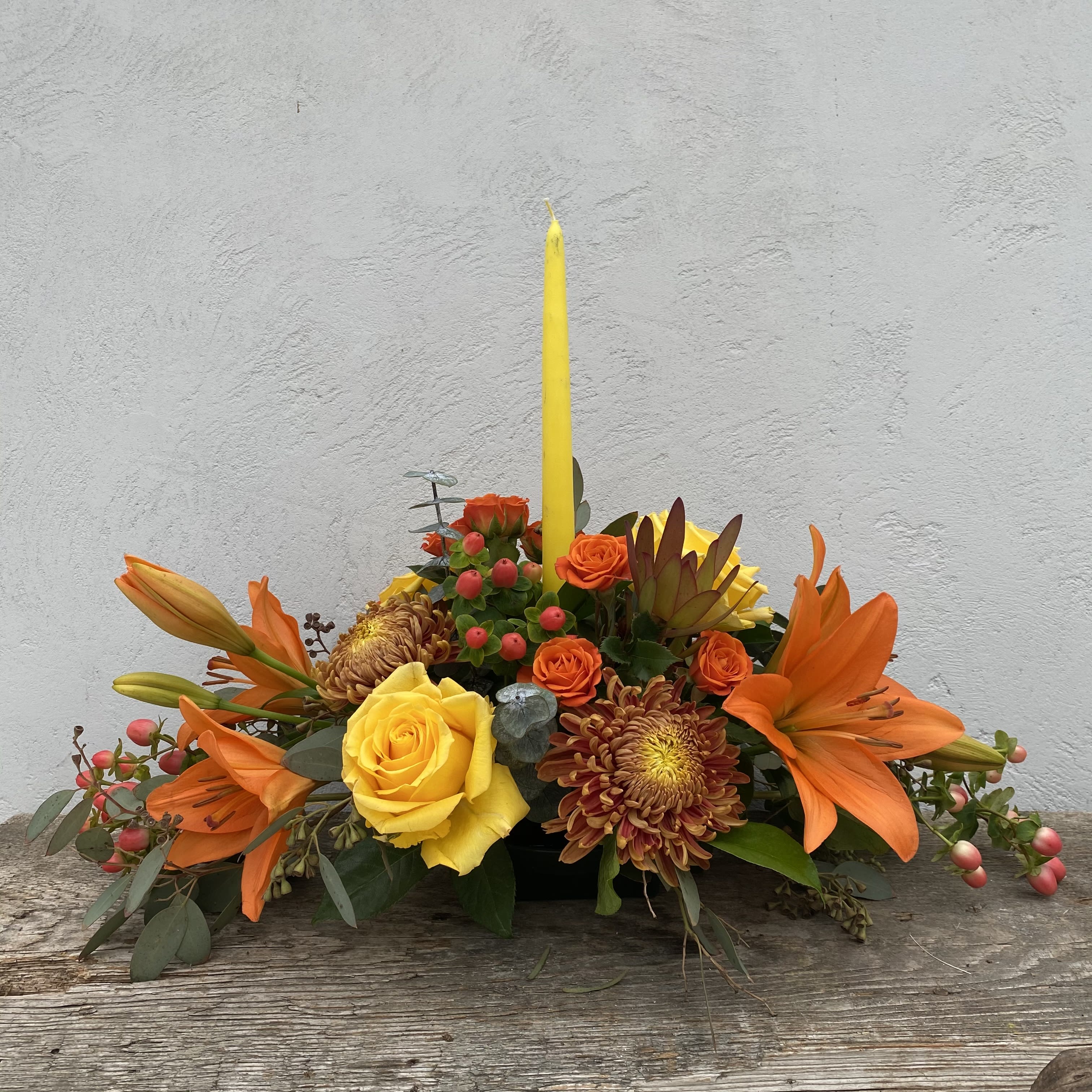 Thanksgiving Centerpiece Thanksgiving Centerpiece - A mixture of fall flowers with a candle to adorn your thanksgiving table. The centerpiece is 20 inches long and 18 inches tall.