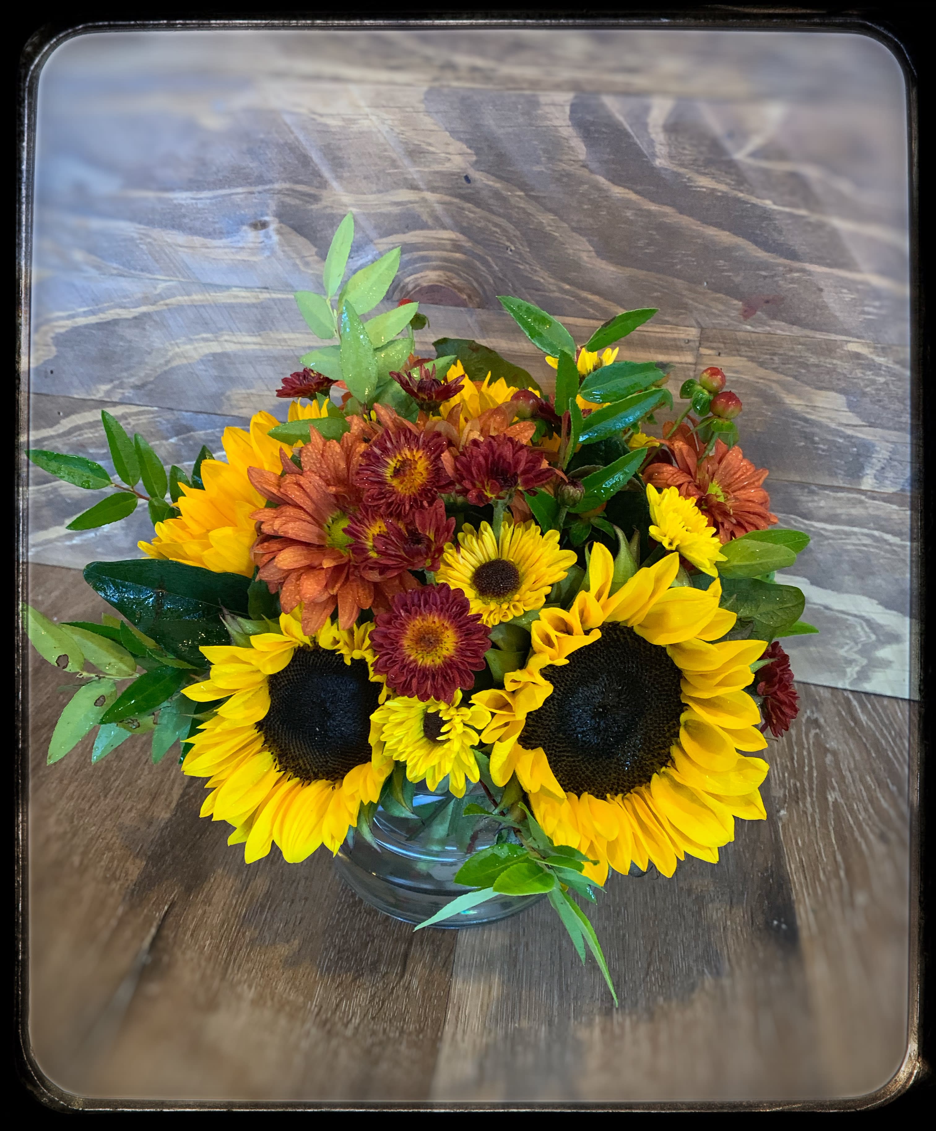 Autumn Skies - Brighten their day with this gift of sunny blooms. Presented in a beautiful glass container.