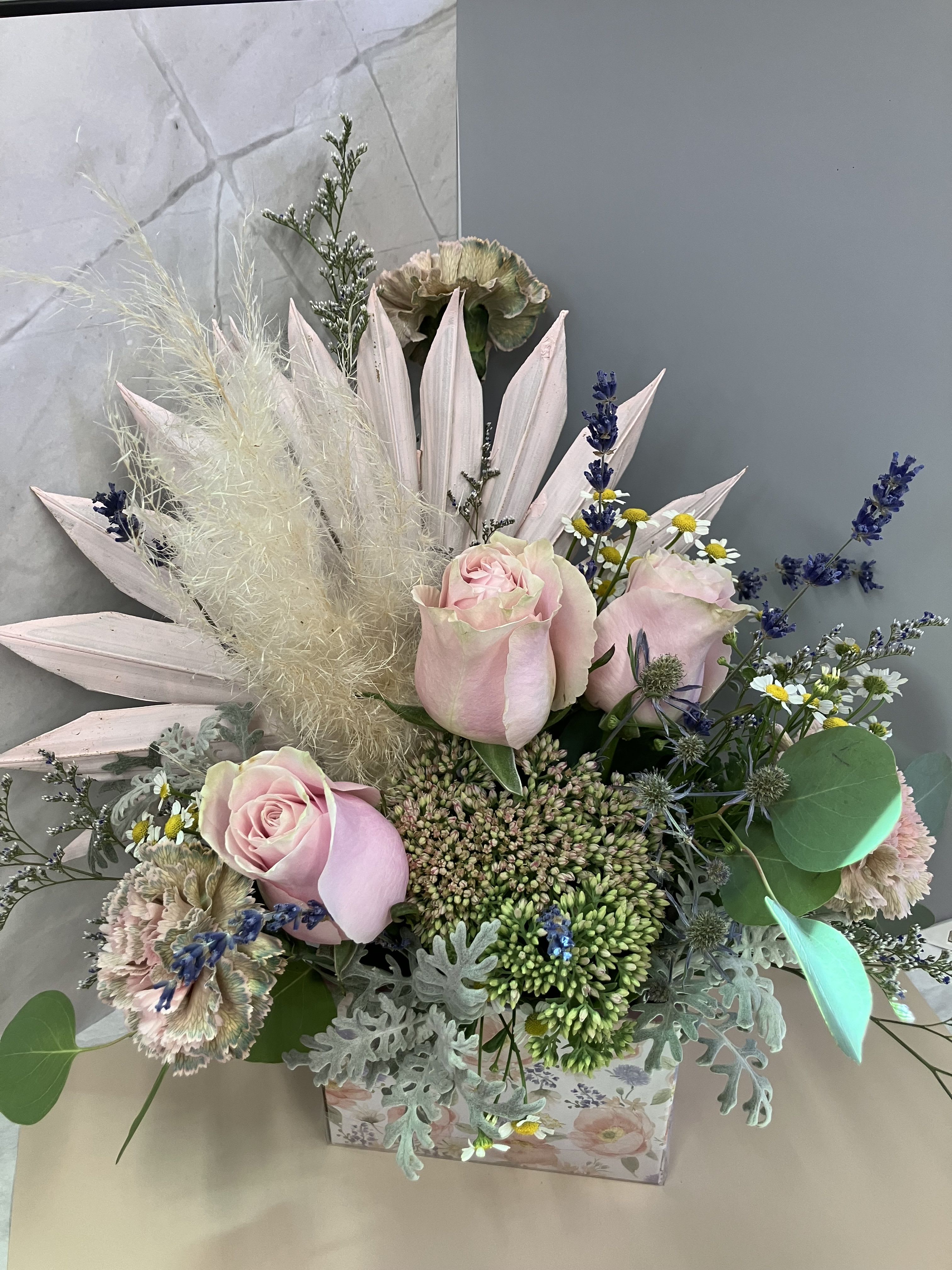 Boho Box Boho Box - Soft pink roses, lavender and sedum with pink decor and pompous grass create a sweet boho arrangement in a floral box.
