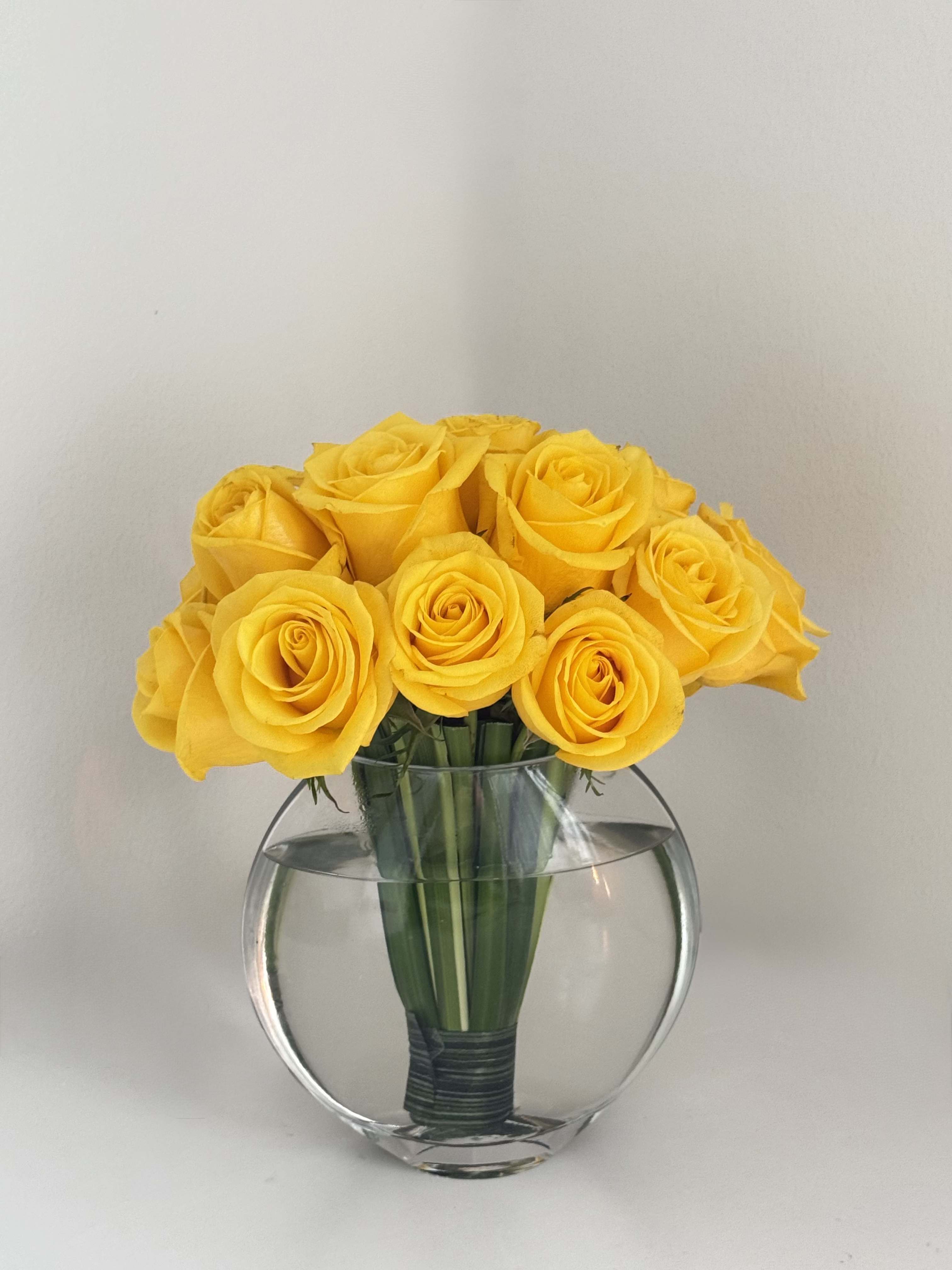 Golden Vase Arrangement - A radiant display of premium yellow roses, meticulously arranged in a modern vase. This timeless design is an elegant gift for any celebration, a sophisticated statement piece, or a simple way to brighten someone's day.  Available Size:  Medium (M): 15 roses for $75.  Details:   The vase is included in the price