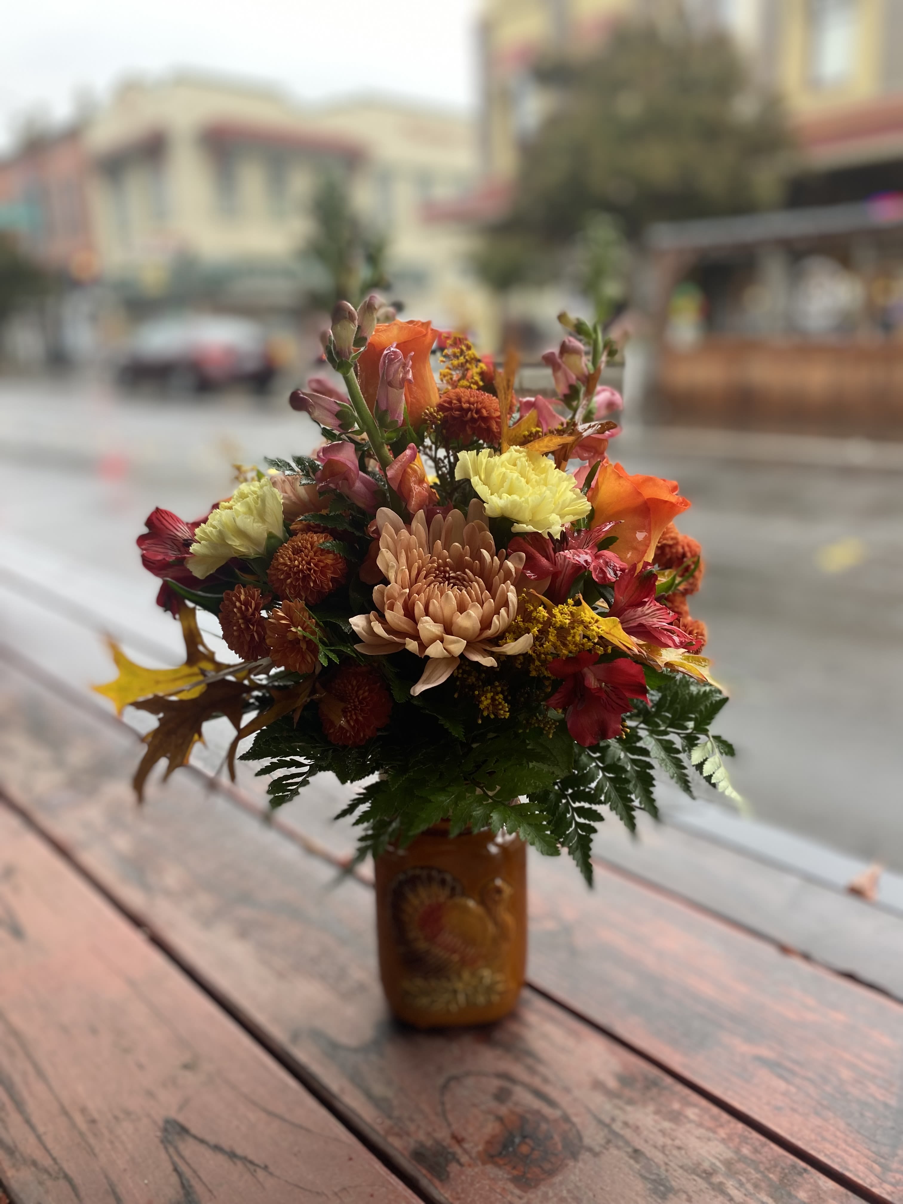 Harvested Blessings Harvested Blessings - Celebrate the season of gratitude with our "Harvested Blessings" Thanksgiving floral arrangement. Arranged in a rustic mason jar adorned with a charming turkey design, this vibrant bouquet brings the beauty of autumn right to your table. Stocked full of fresh blooms including carnations, roses, button mums, chrysanthemums, alstroemeria, solidago, and fall leaves.