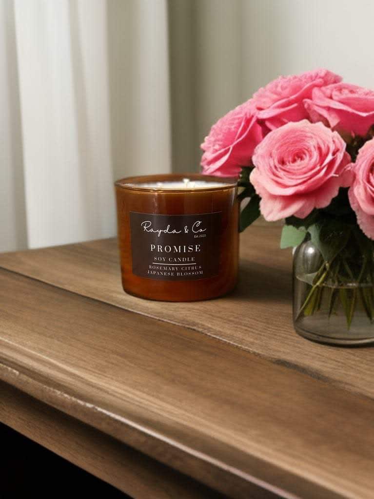 Promise Candle 16oz Promise Candle 16oz - Experience the artistry of Rayda & Company's handcrafted 3 wick soy candles, lovingly poured into amber jars. Our "Promise" soy candle captivates with a gentle blend of Rosemary, Citrus, and a hint of Japanese Blossom, evoking a sense of renewal and serenity. Let the delicate fragrance and warm glow of this candle fill your space with promises of tranquility and bliss.