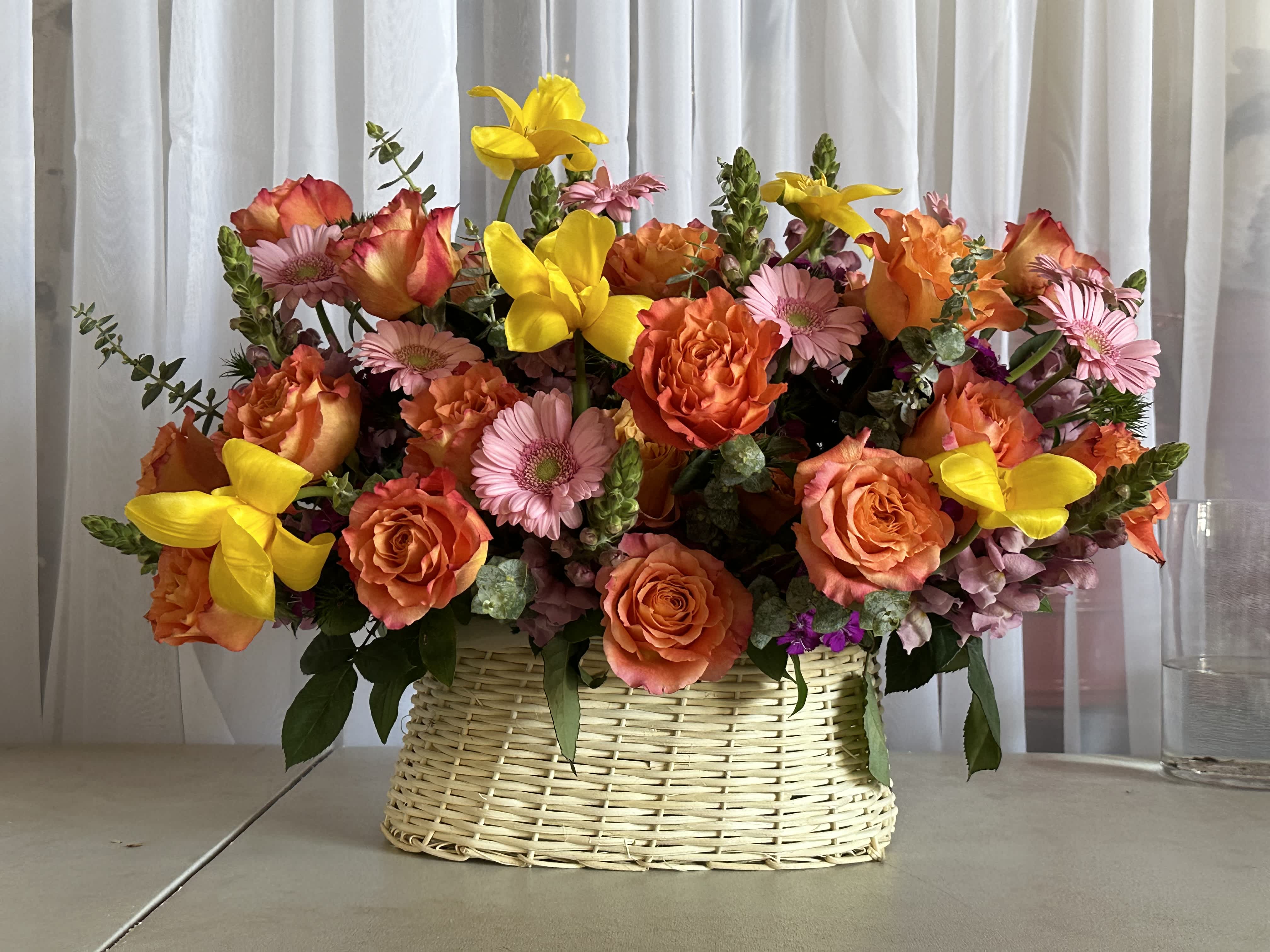 Vibrant Meadow Basket - Includes:   - Orange roses  - Yellow tulips - Pink gerber - Lavender stock or purple snapdragon replacement