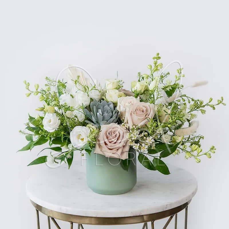 Jade - Soft, serene, and naturally elegant — Jade is a calming arrangement that brings effortless beauty to any space. Featuring blush roses, white lisianthus, fresh greens, and a striking succulent at its center, it’s thoughtfully accented with dried textures and airy filler florals.  Designed in our signature sage green vase, Jade is perfect for sending comfort, expressing gratitude, or simply adding a touch of tranquility to someone’s day.